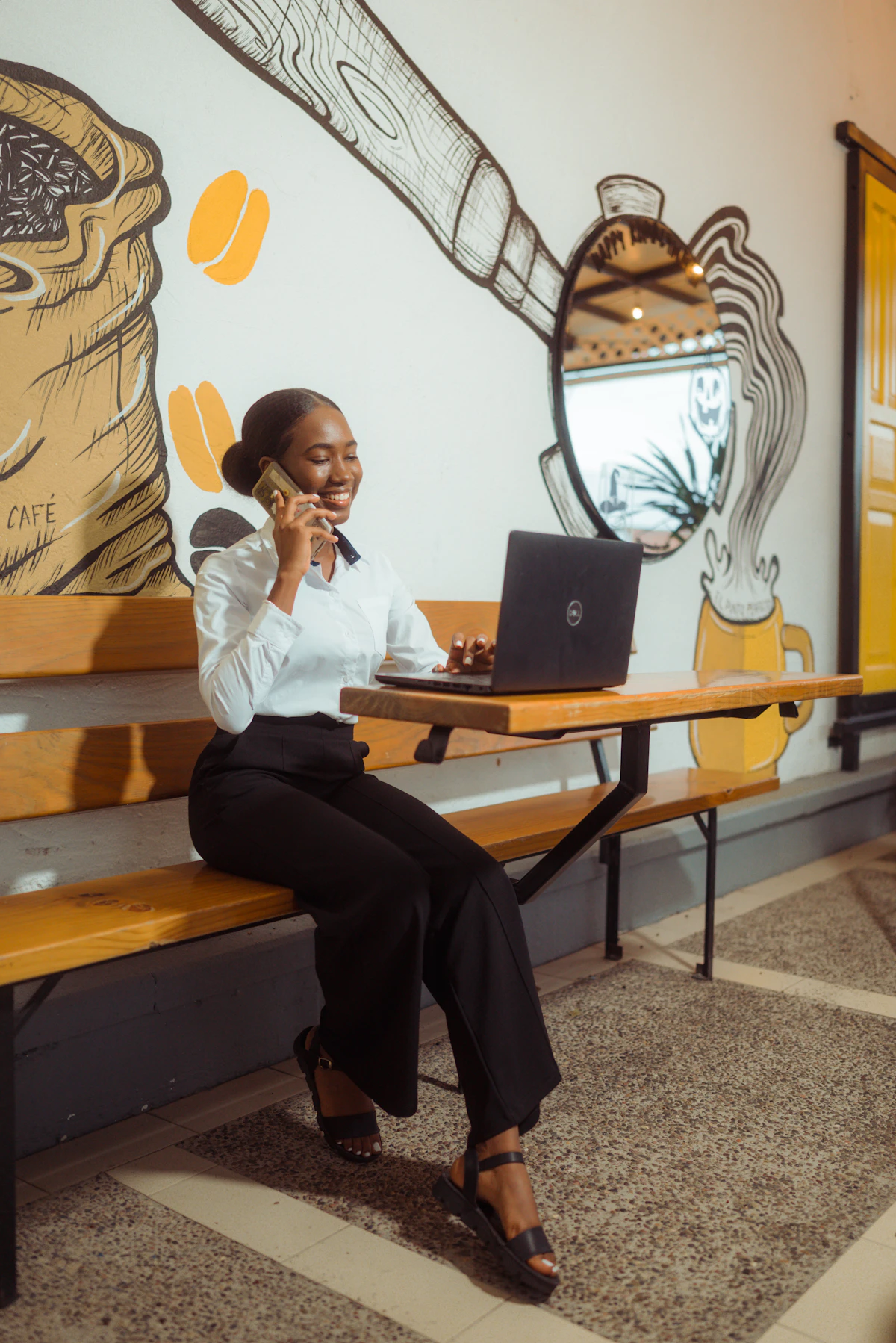 woman taking a call with a laptop in a cafe