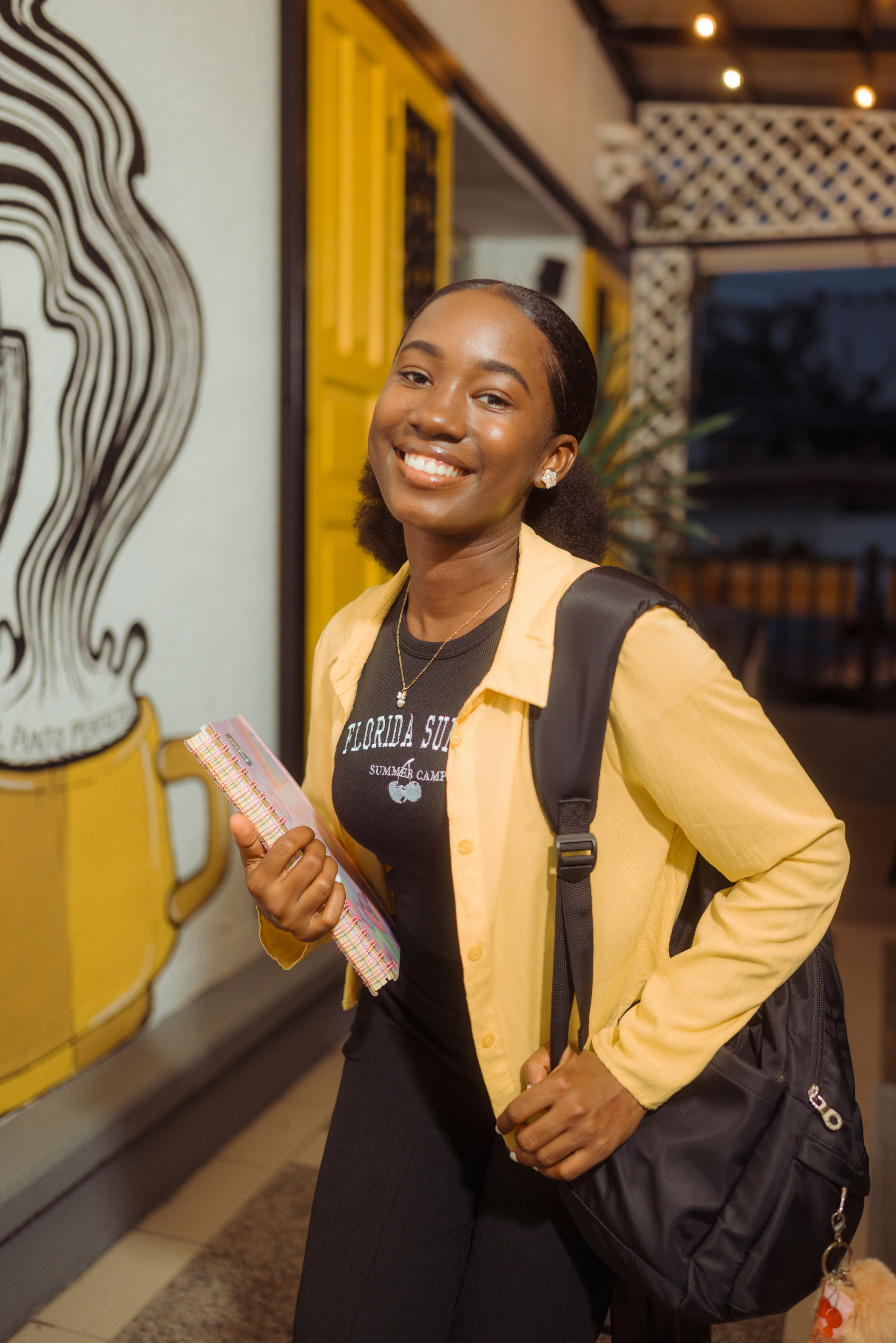 Smiling student with backpack and notebooks