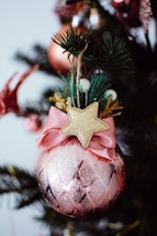 A pink christmas ornament with a gold star