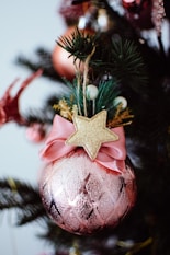 A pink christmas ornament with a gold star