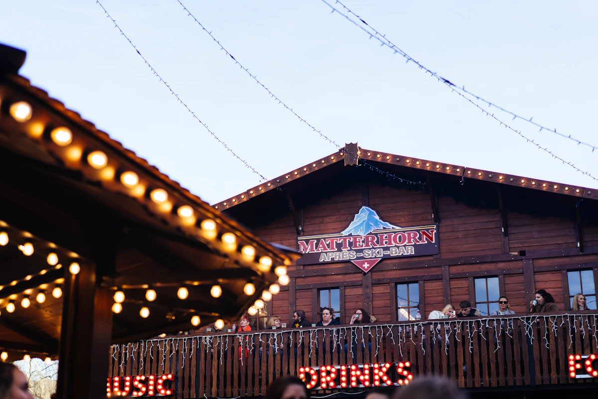 An alpine bar lit up at night with people on the balcony