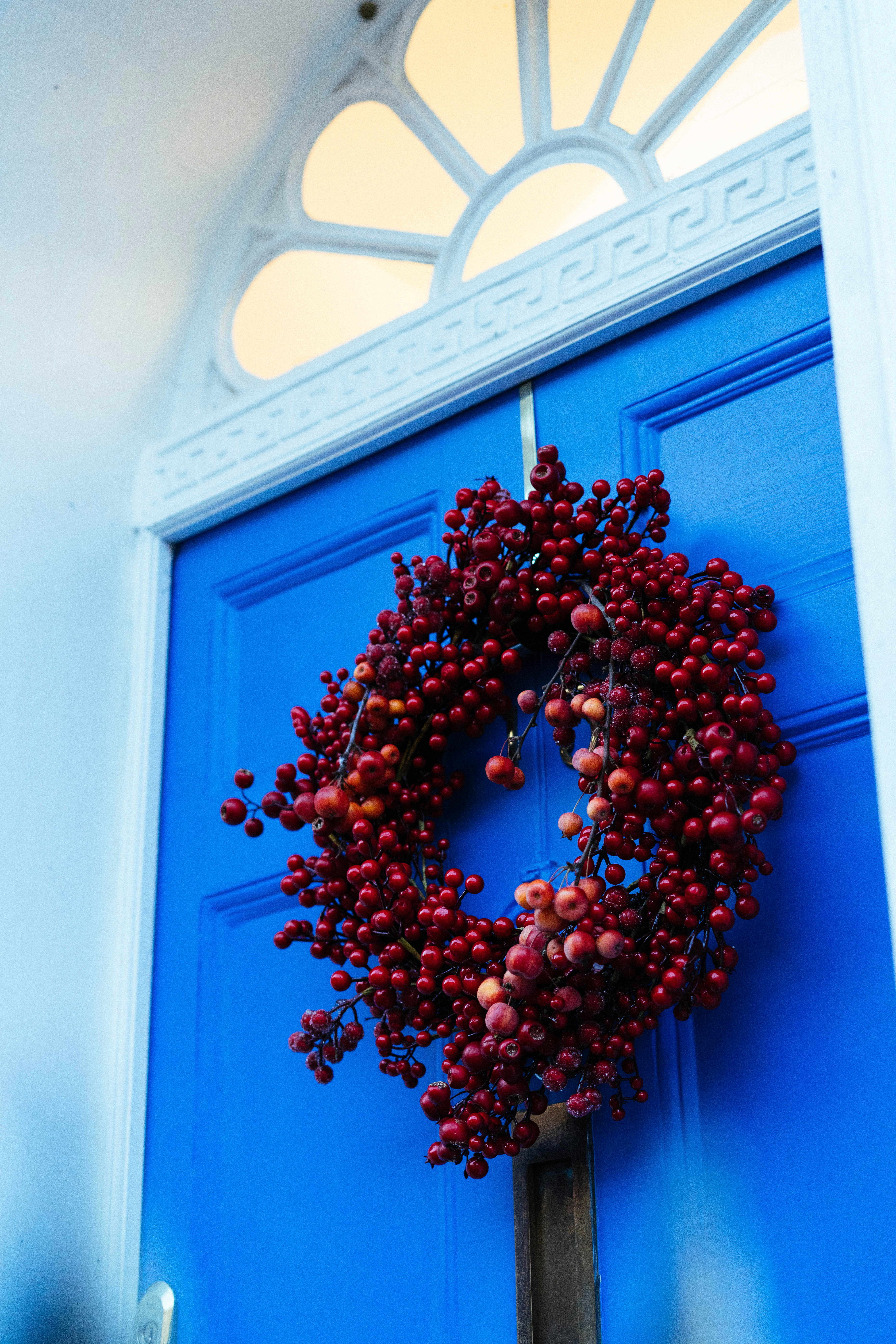 A bright blue door with a red berry wreath.