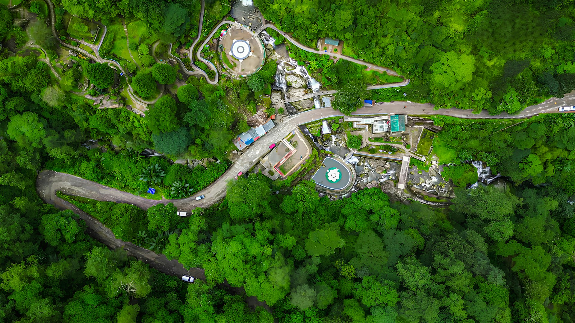 Aerial view of a winding road through lush green forest.