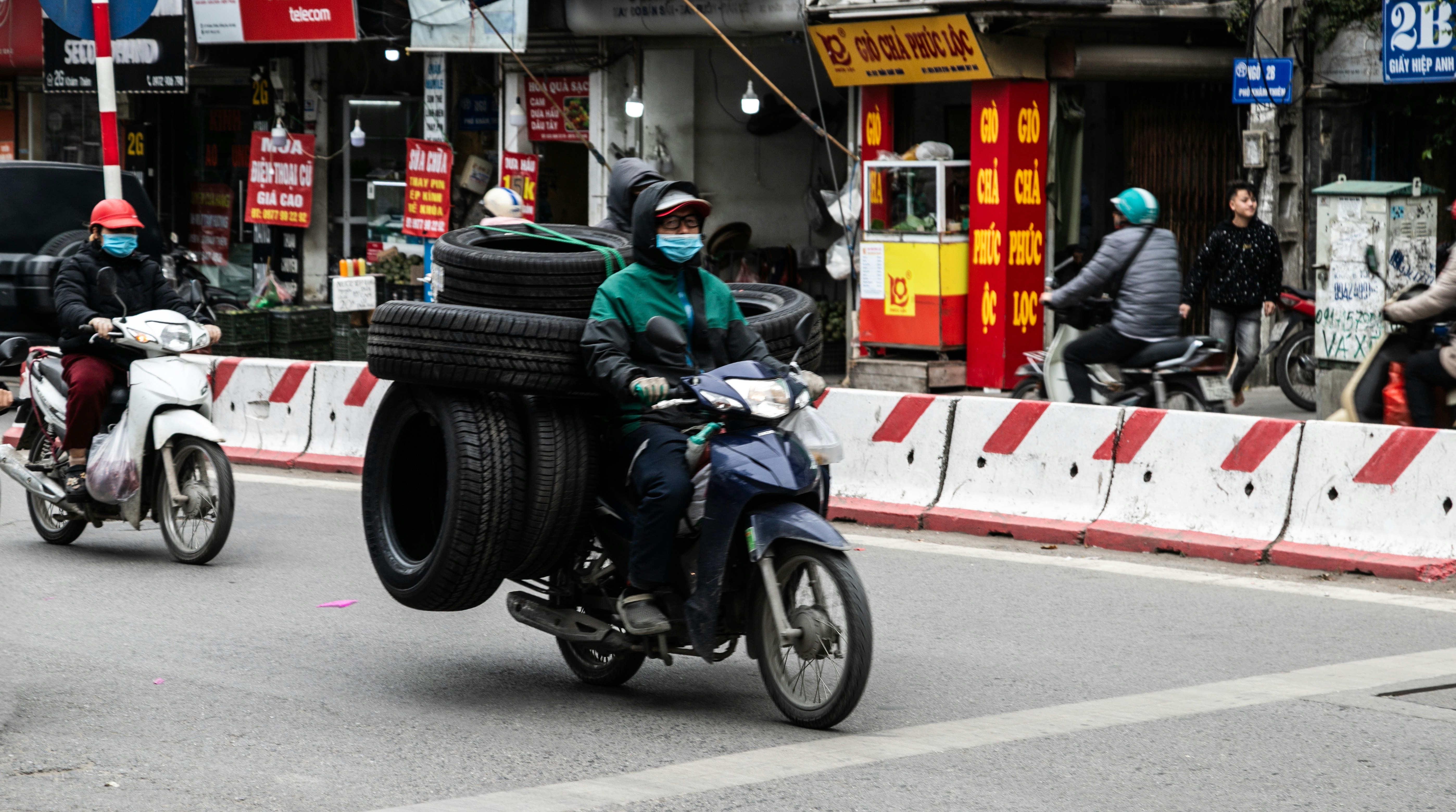 Motorcyclist transports large stack of tires on city street