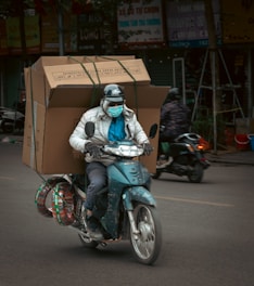 Man on a scooter carrying large boxes