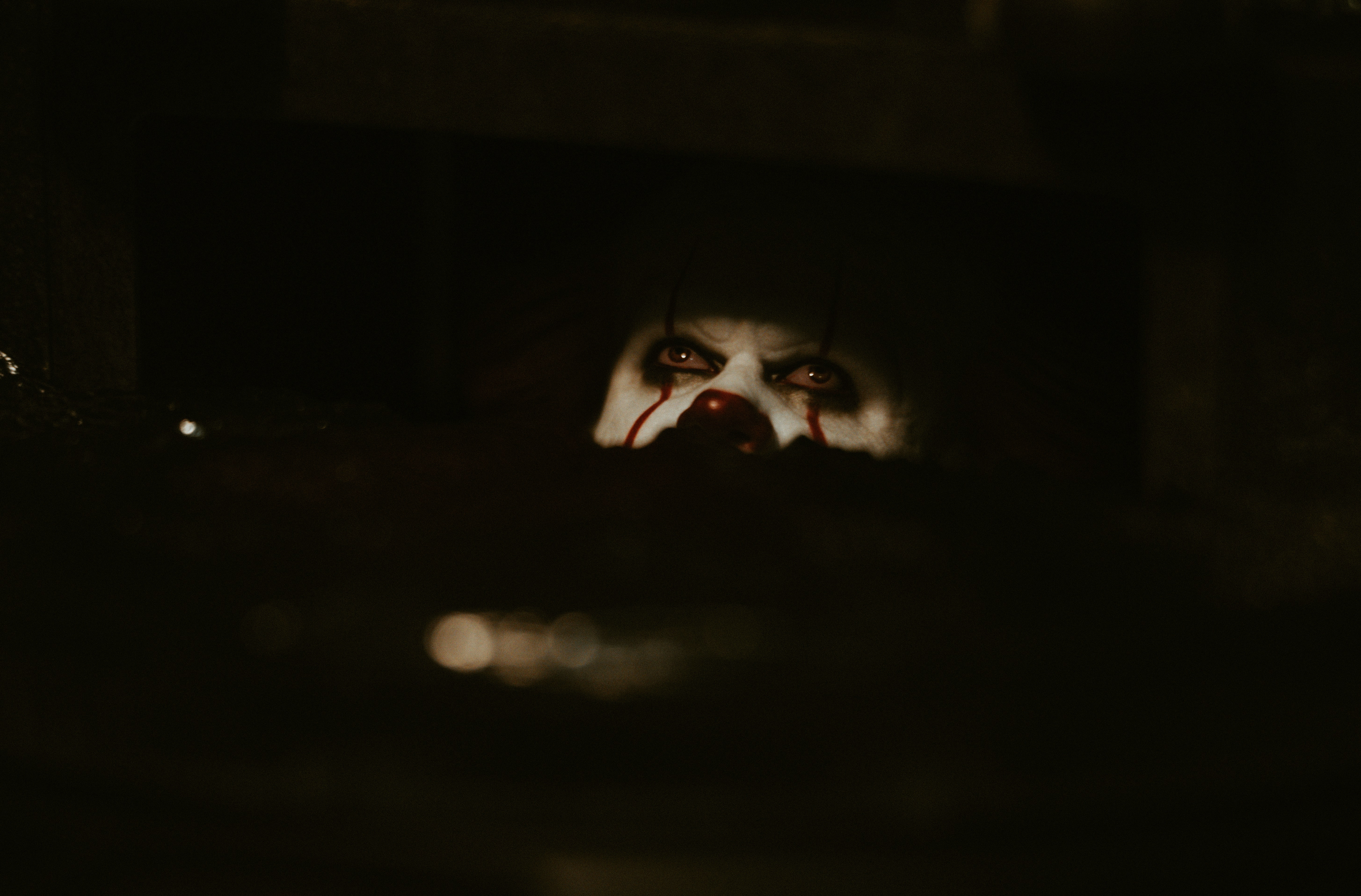 A creepy clown peeking from darkness