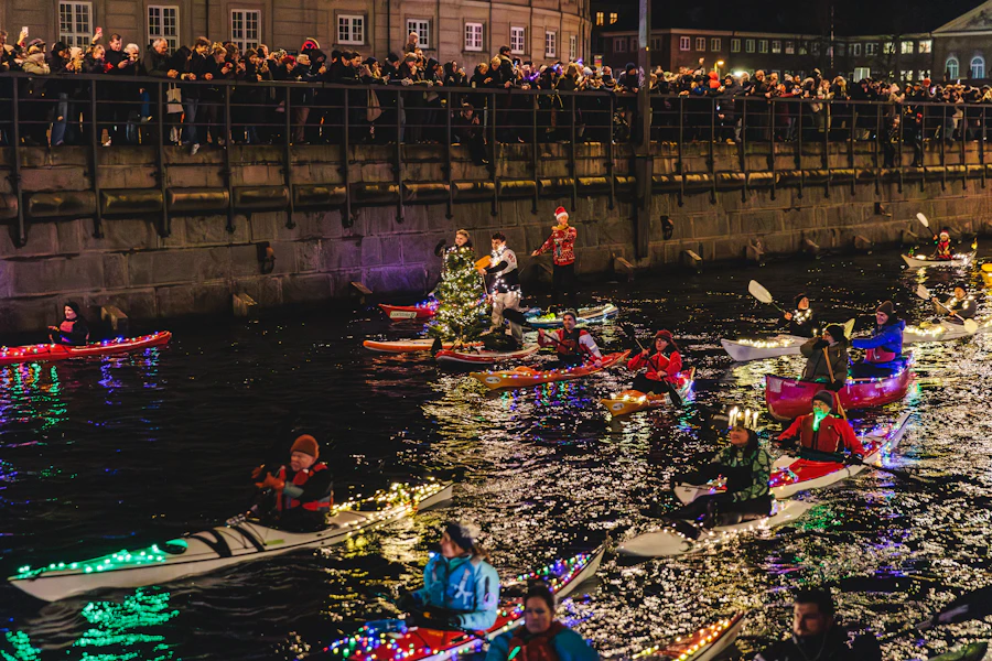 Kayaks lit with holiday lights parading on the water at night