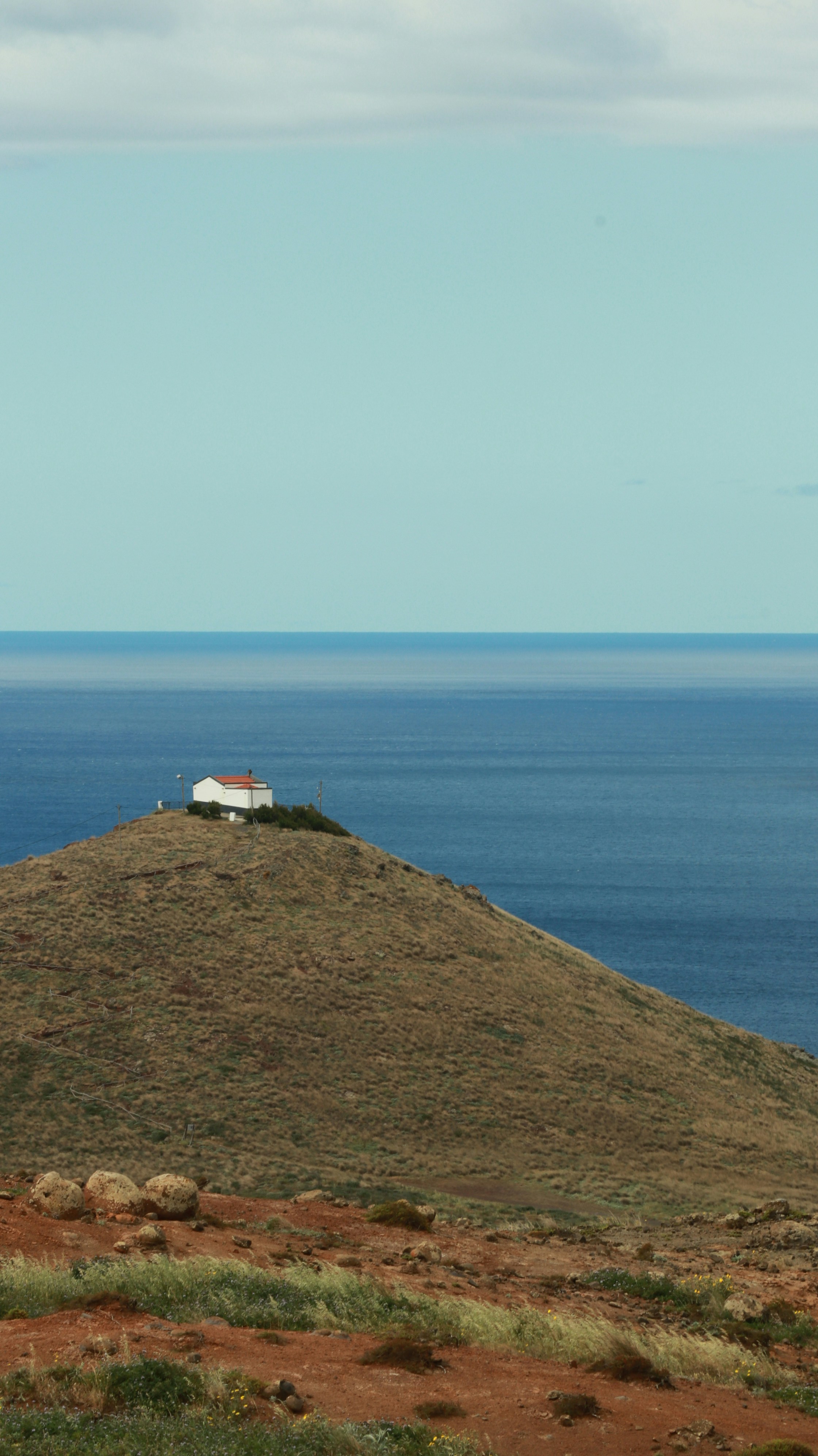 Piccolo edificio bianco su una collina erbosa che domina l'oceano