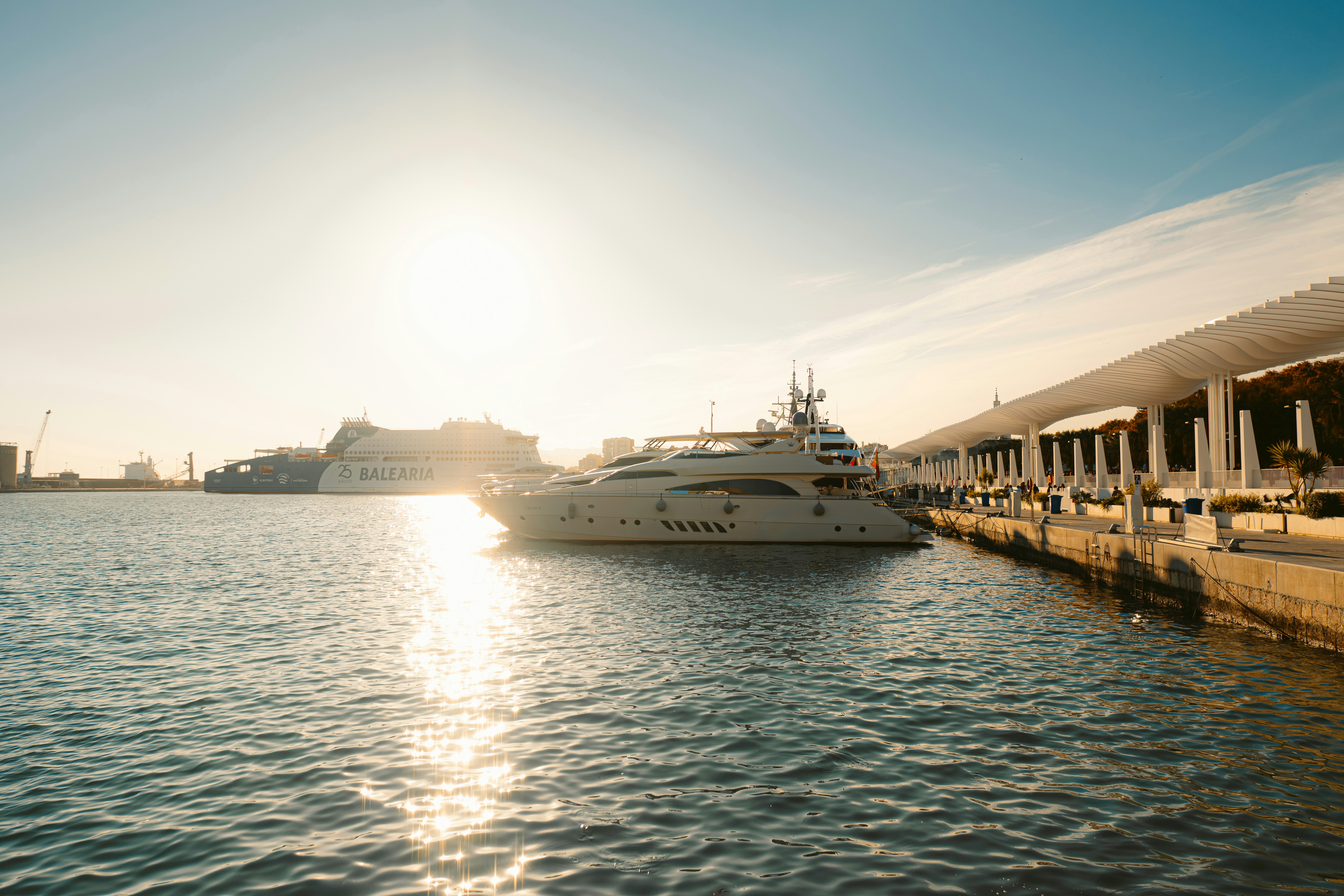 Luxury yachts docked at a harbor during sunset.