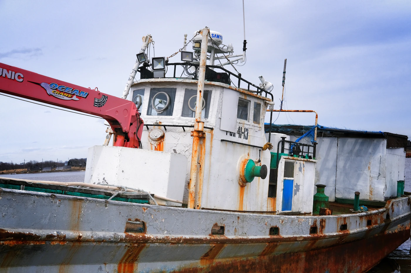 Weathered commercial fishing vessel with a deck crane, the kind of working boat whose crew qualify as Jones Act seamen