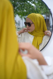 Woman adjusts her yellow hijab and sunglasses