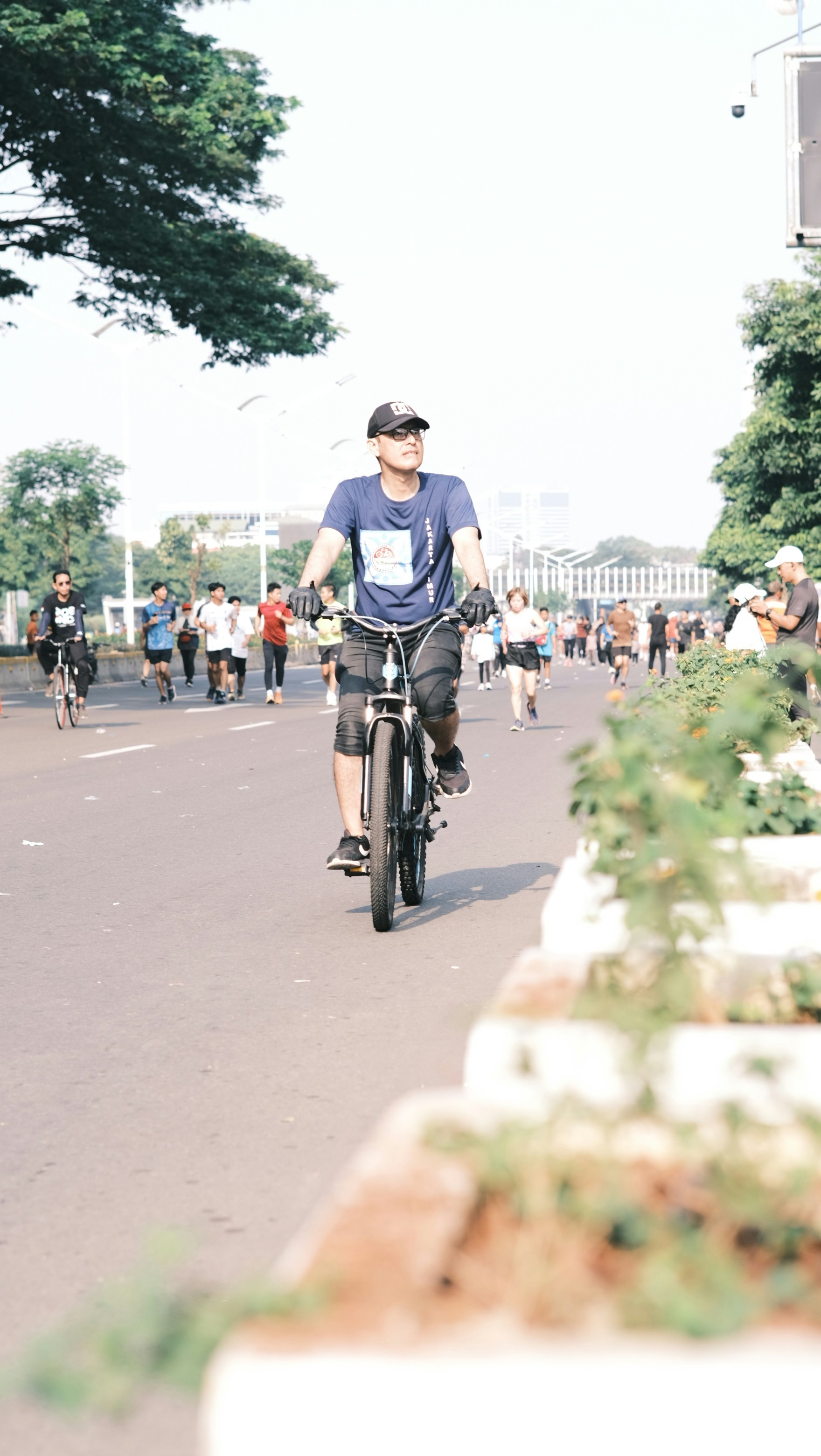 Man riding a bicycle with runners in background