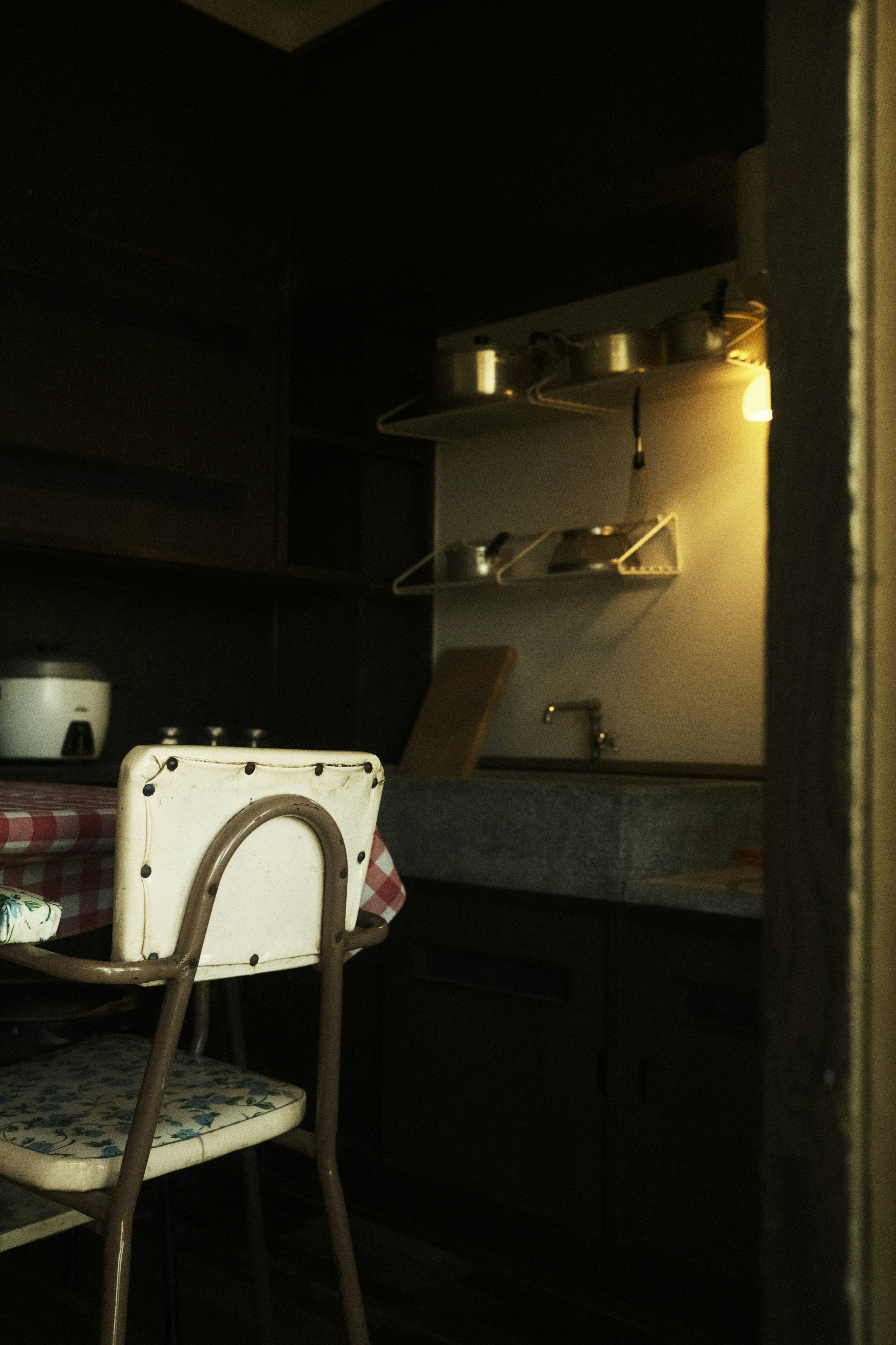 Cocina vintage tenuemente iluminada con silla y fregadero.