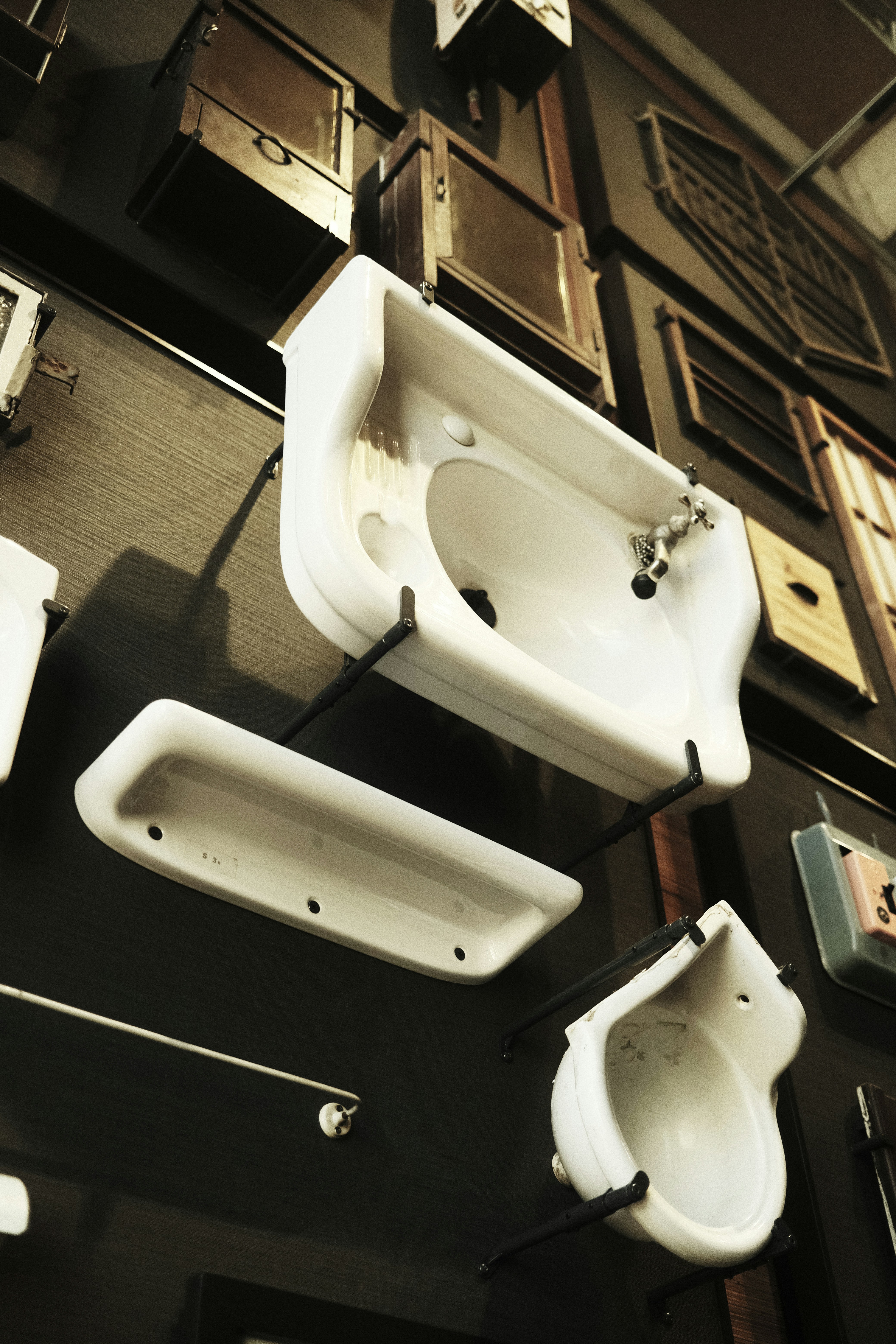 Fregaderos antiguos y accesorios de baño expuestos en la pared.