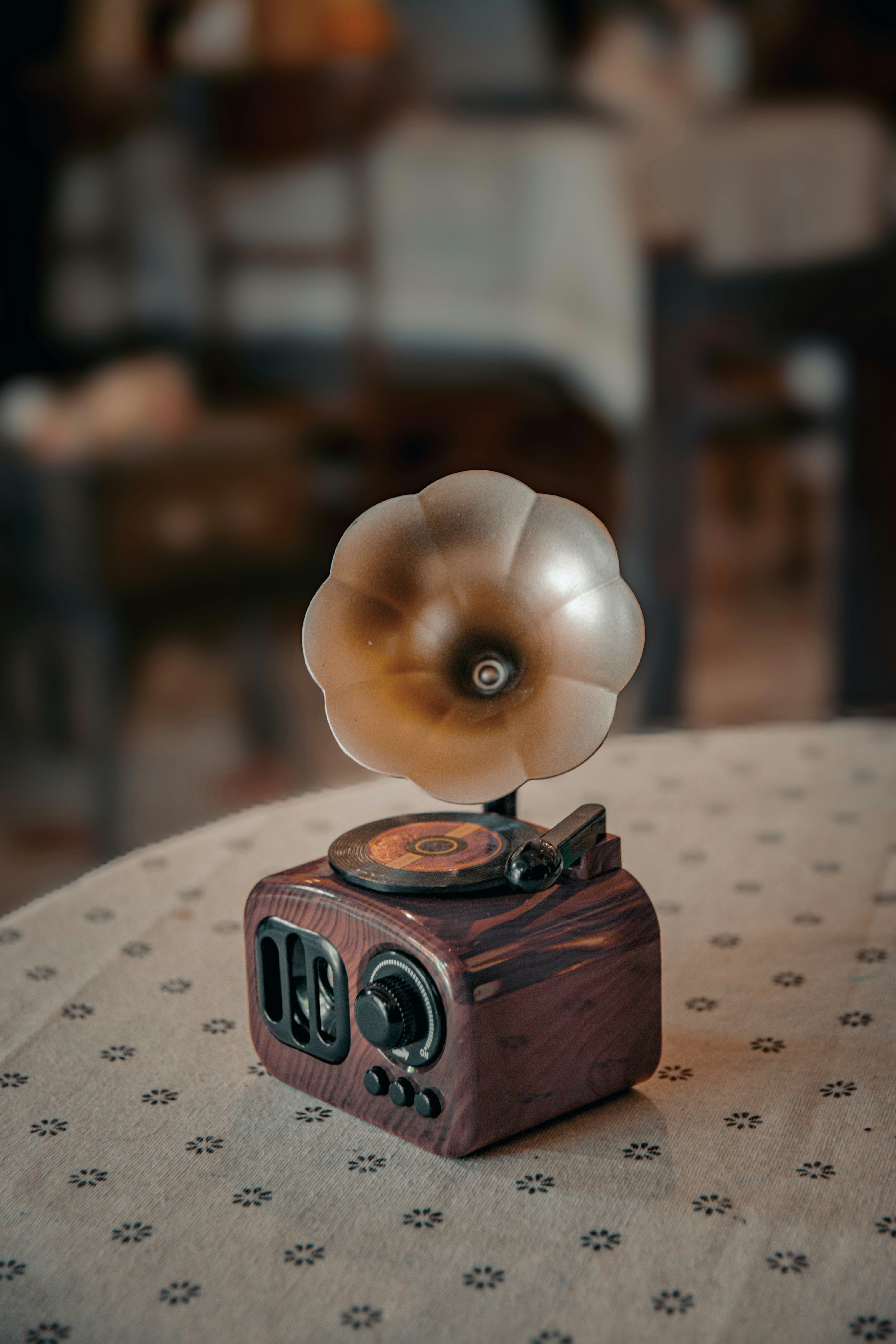 Vintage gramophone speaker on a patterned tablecloth.