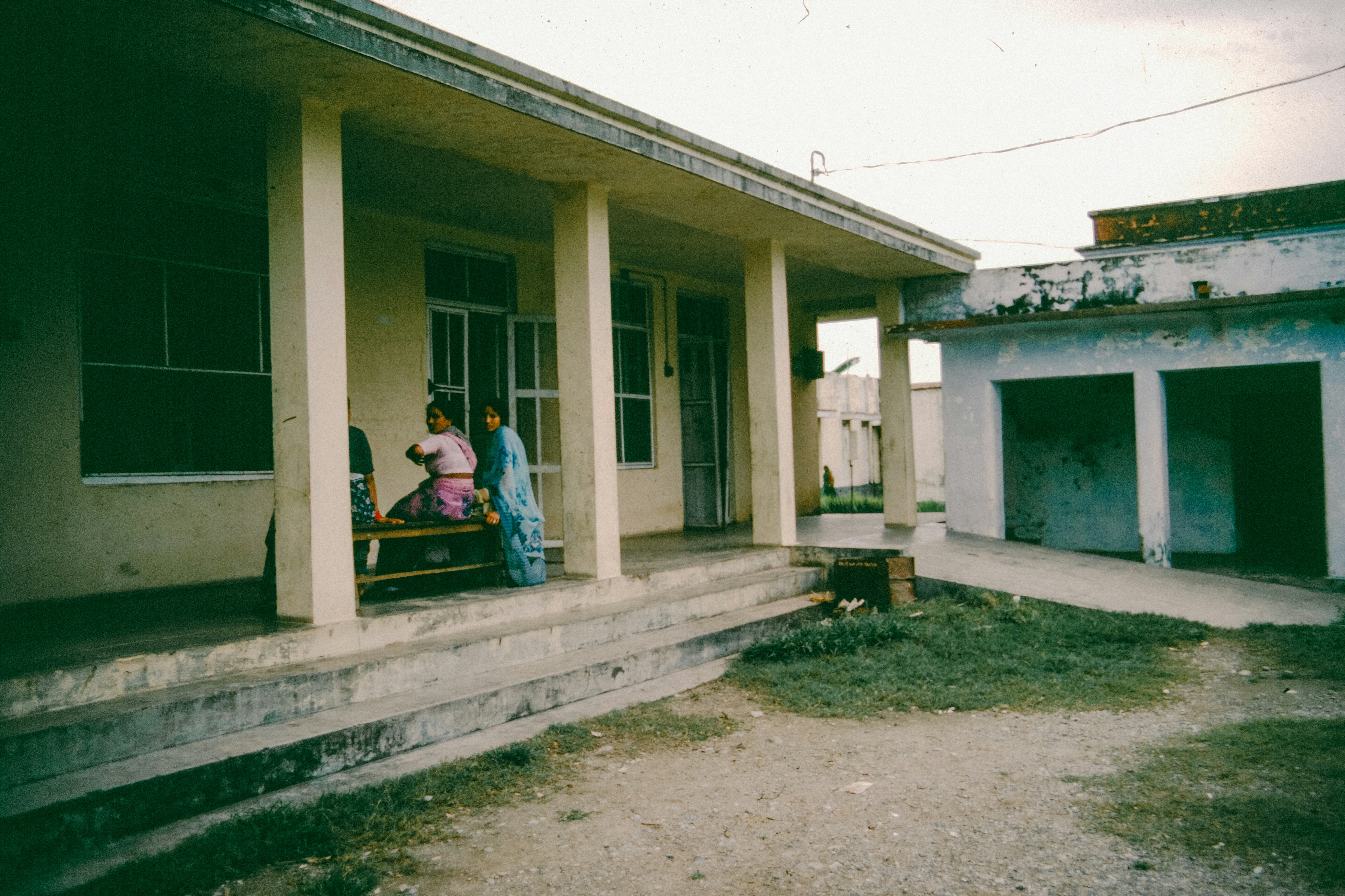 Two people sit on a bench outside a building