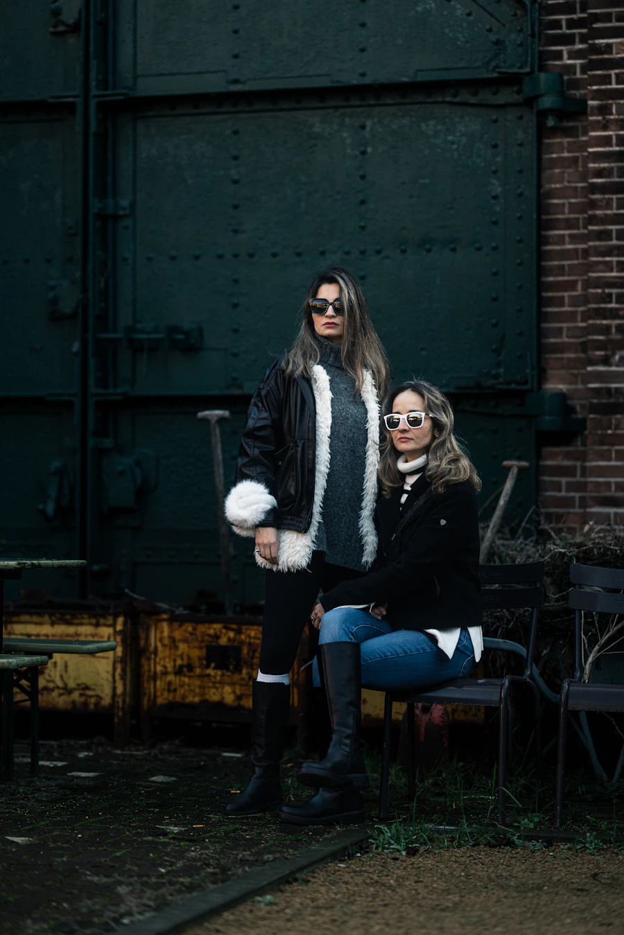 Two women posing in front of a large metal door