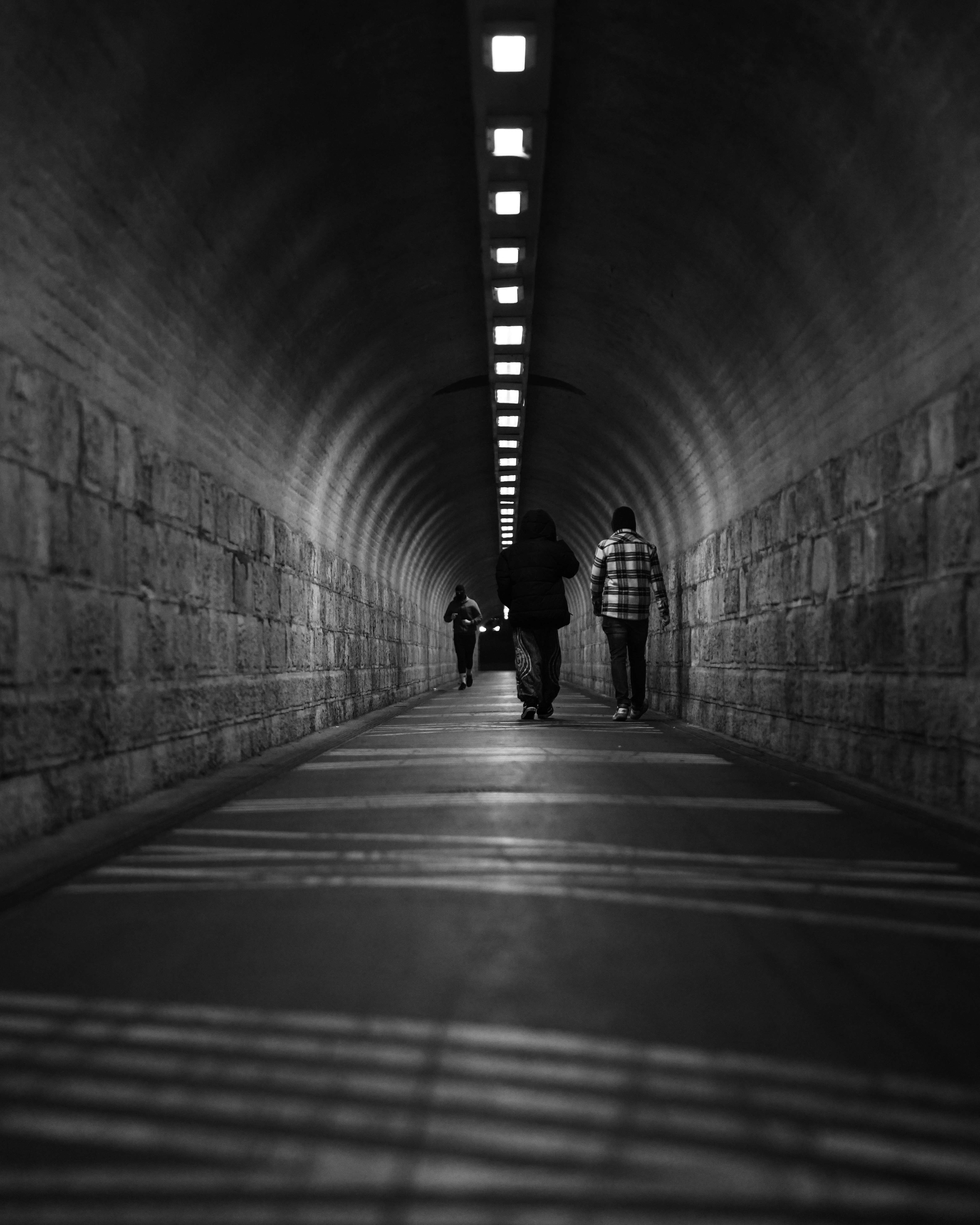 People walk down a long, illuminated tunnel.