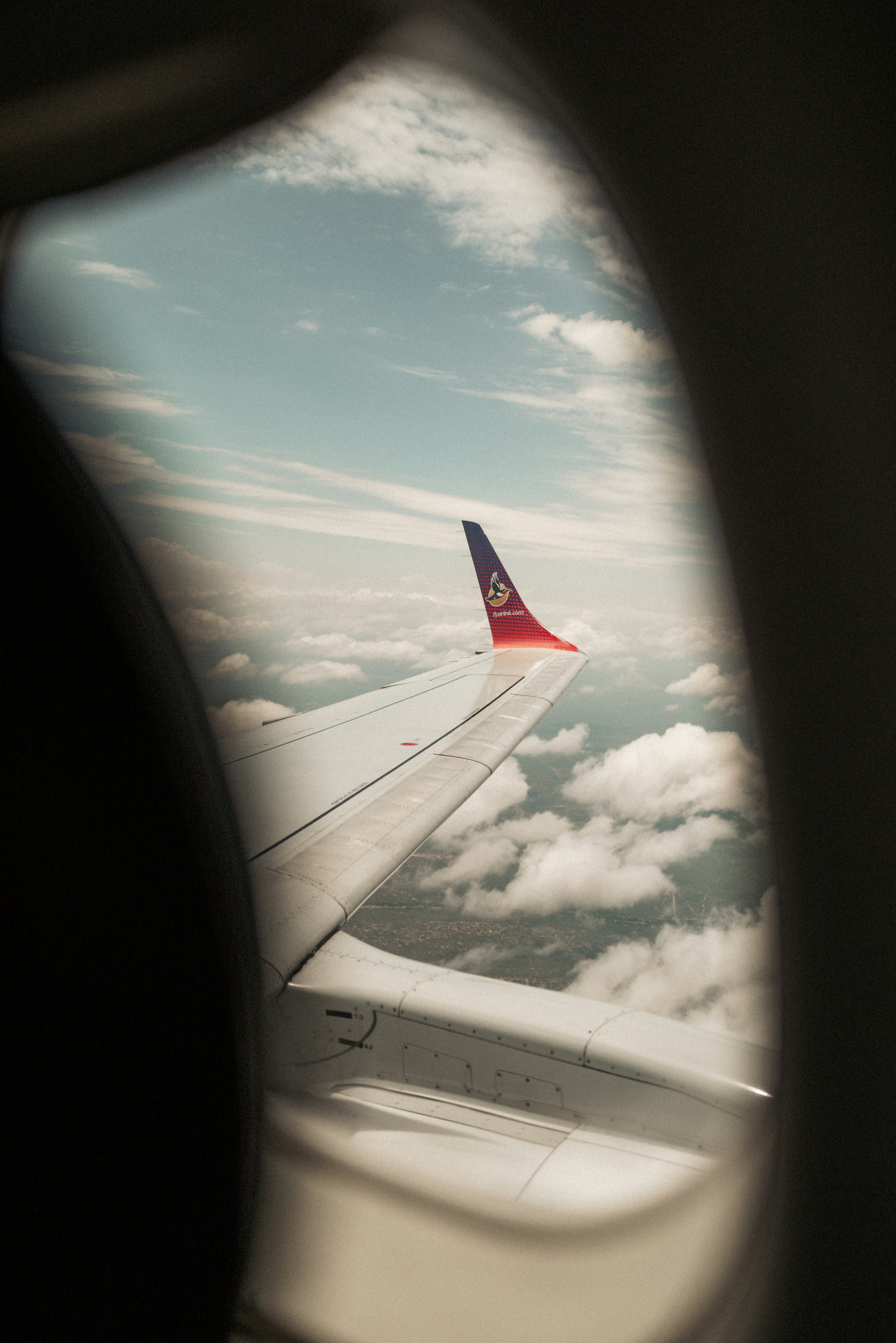 Airplane wing against cloudy sky from window