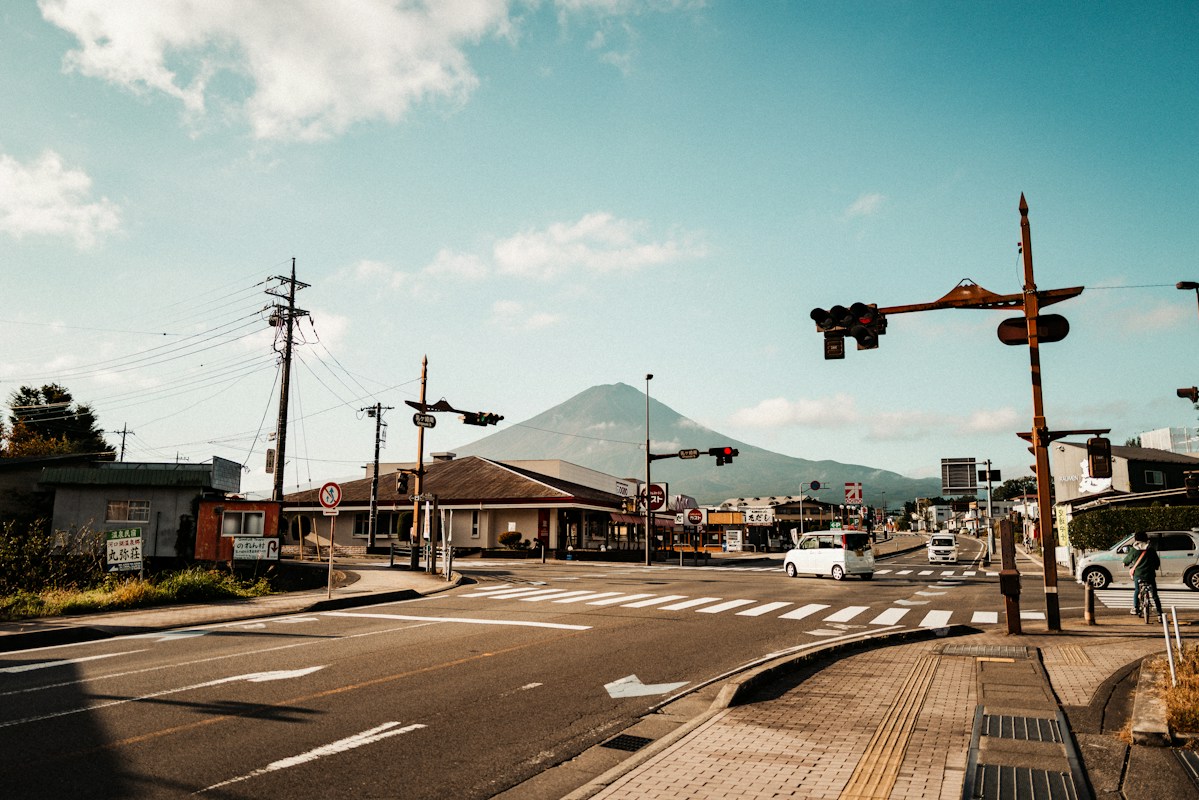 日本市區路口，遠方是連綿山景，前方是待轉的車輛