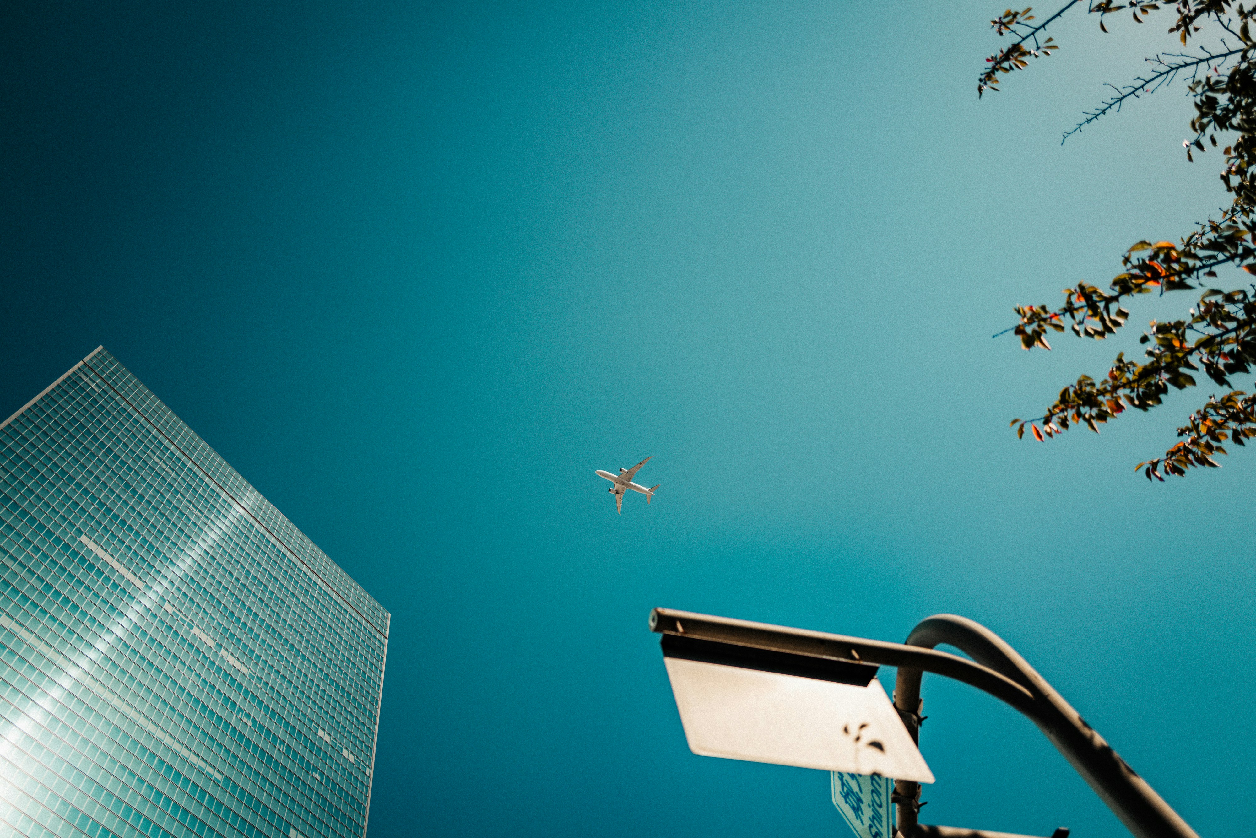 Avião voando perto de prédio moderno sob céu azul claro