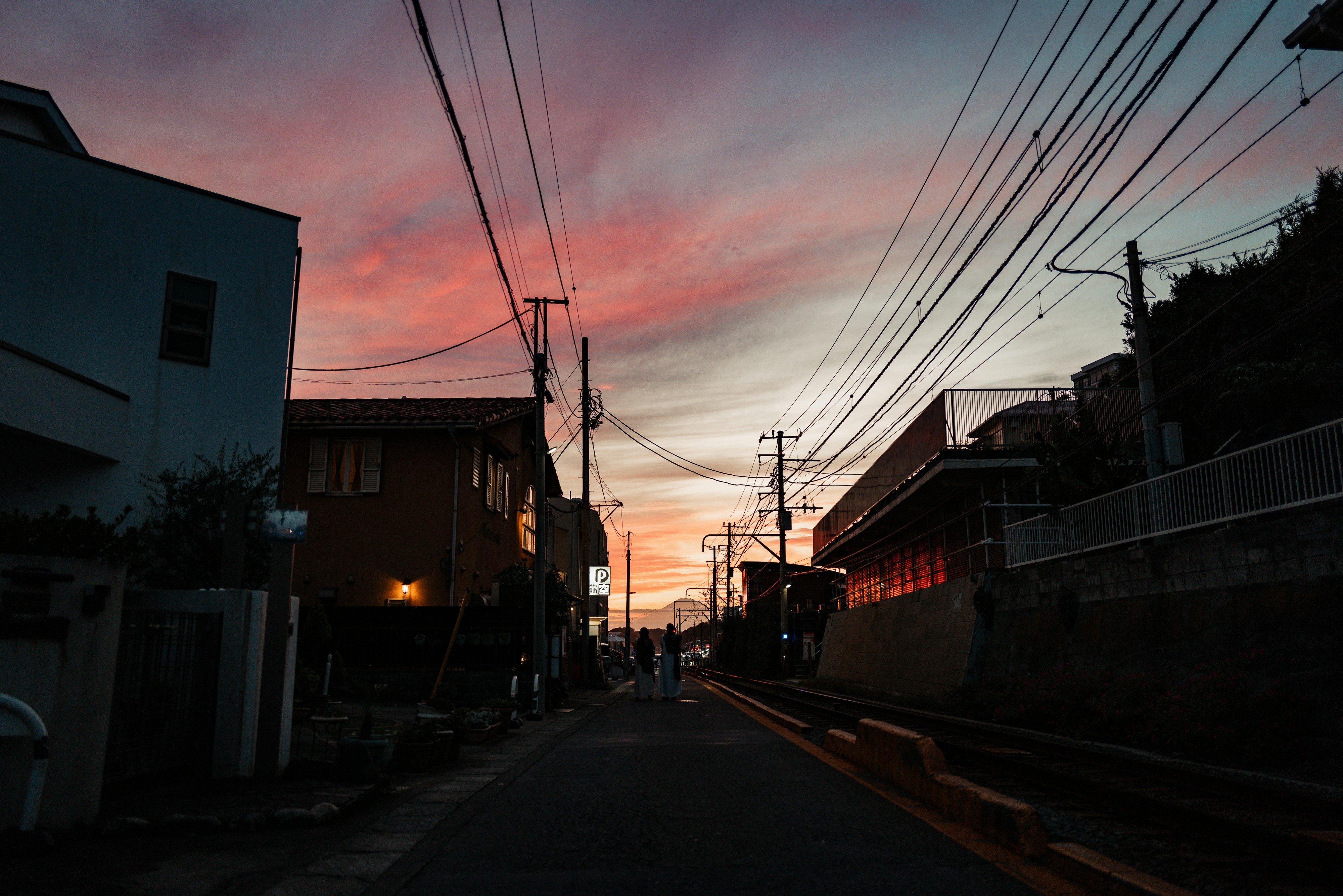 Pôr do sol colorido sobre uma rua tranquila com linhas de energia.