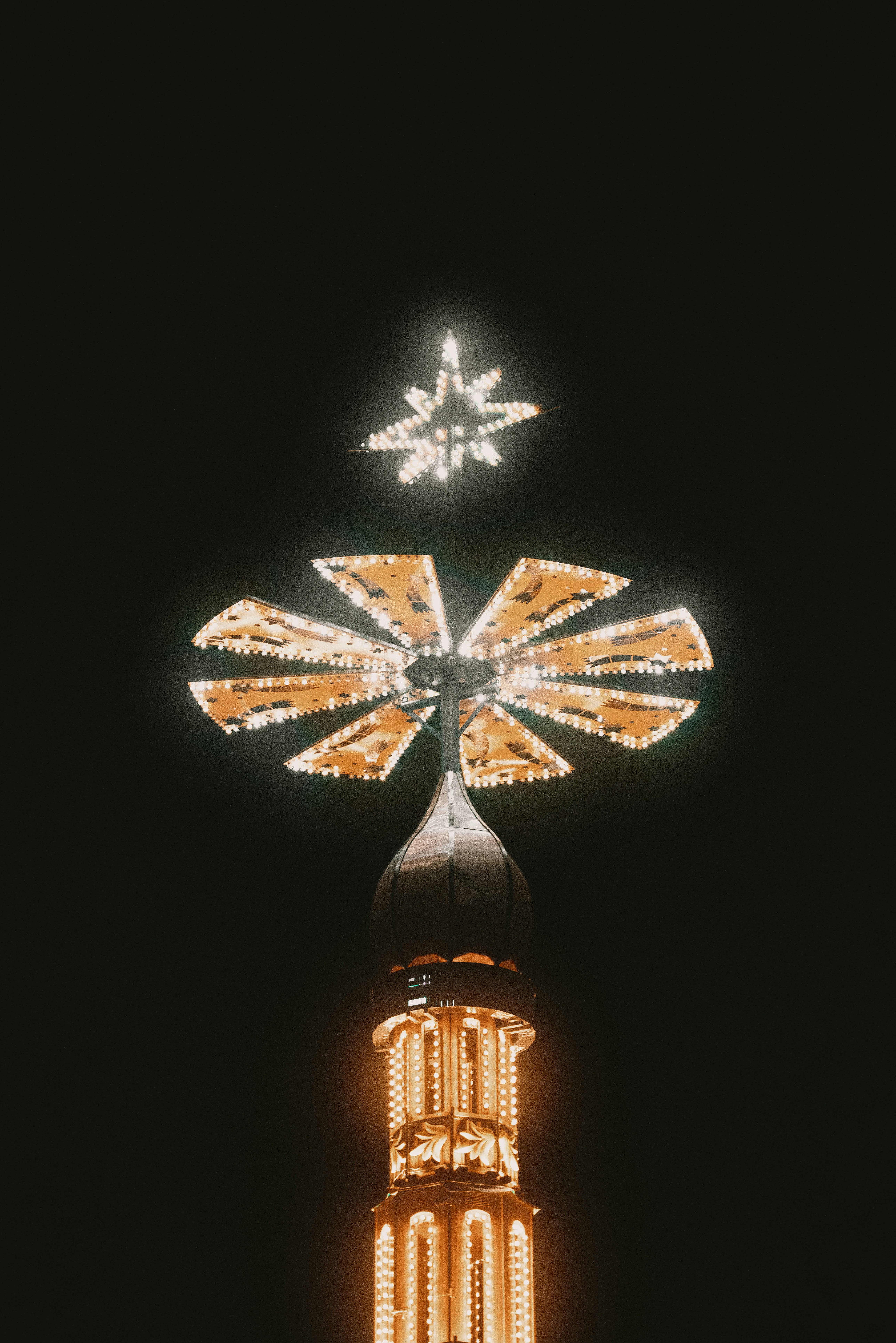 Illuminated carousel top with star against dark sky