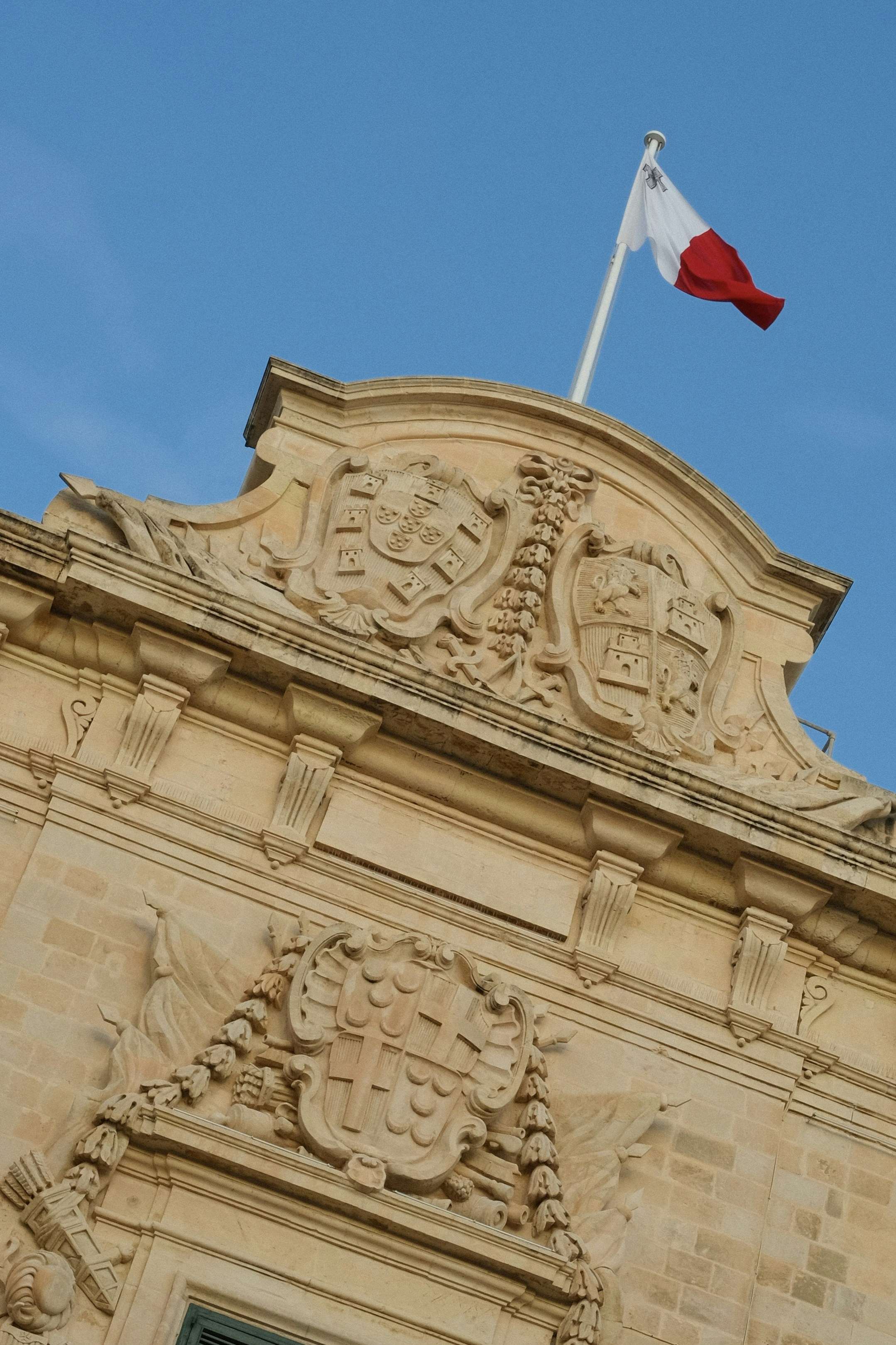 Maltese flag flies atop ornate stone building
