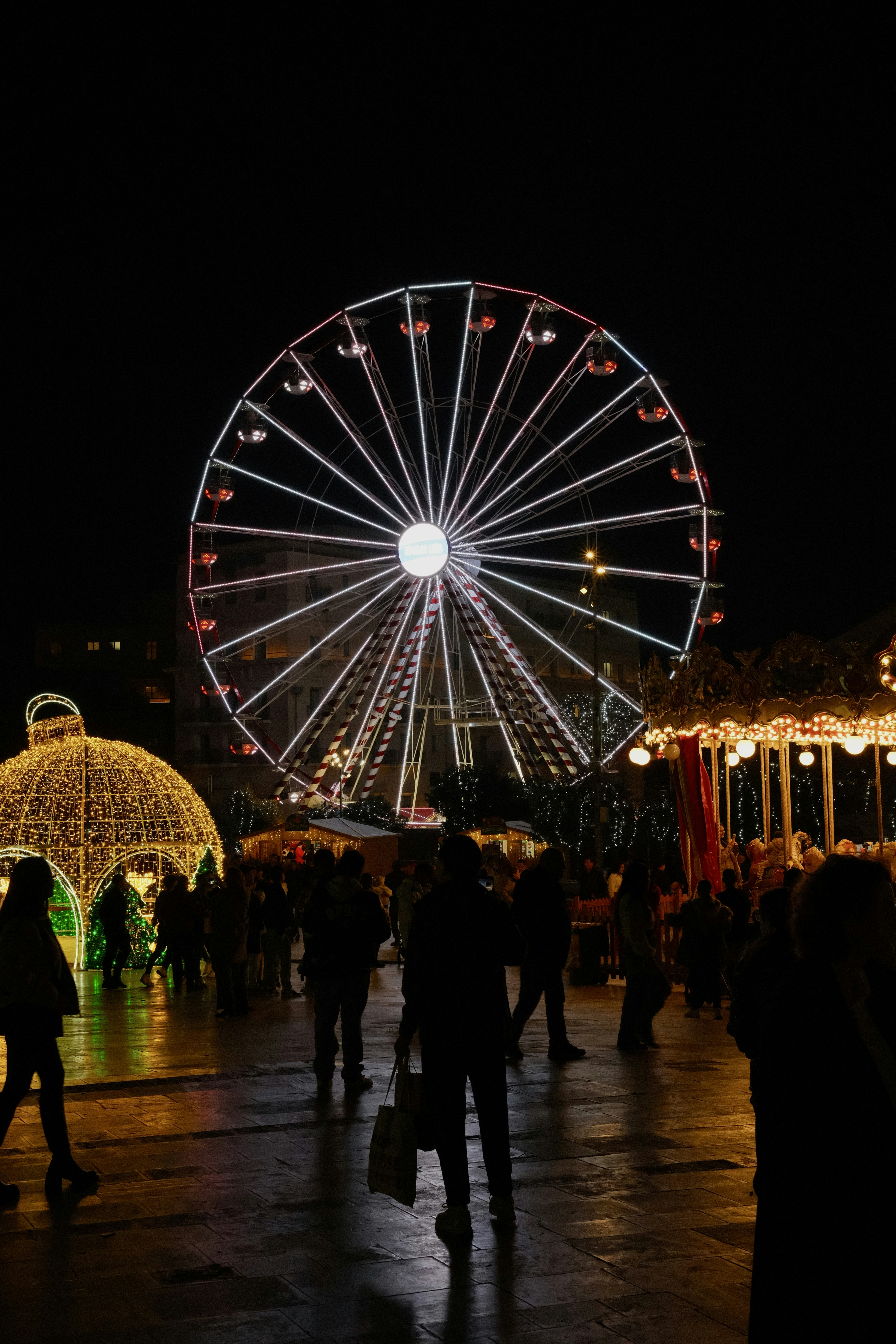 Ferris wheel illuminated at night with people around