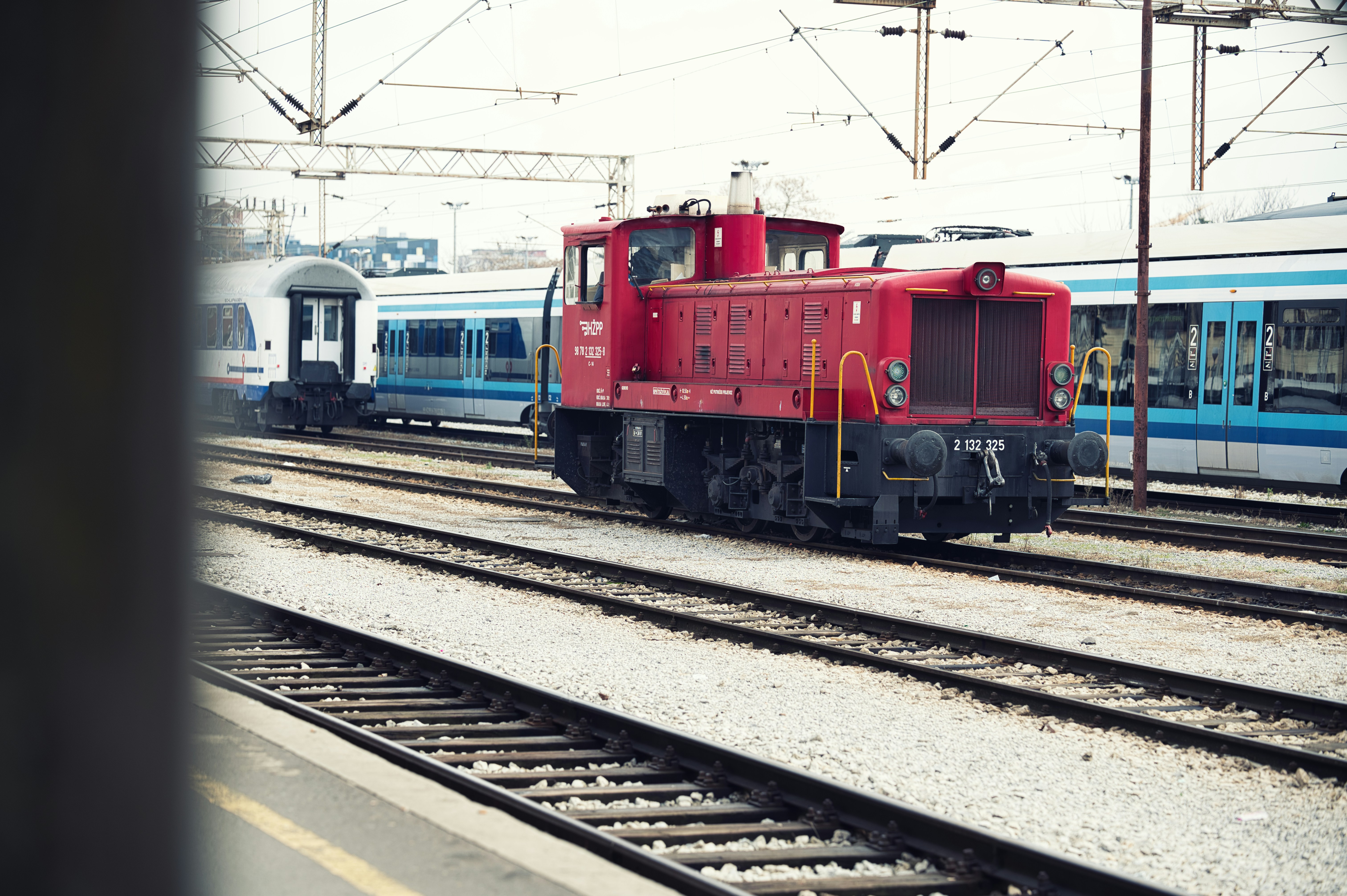 Red train engine parked at a station with other trains.