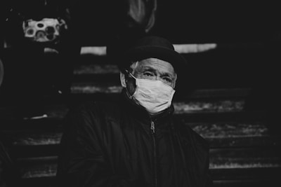 Elderly man wearing a face mask and hat.