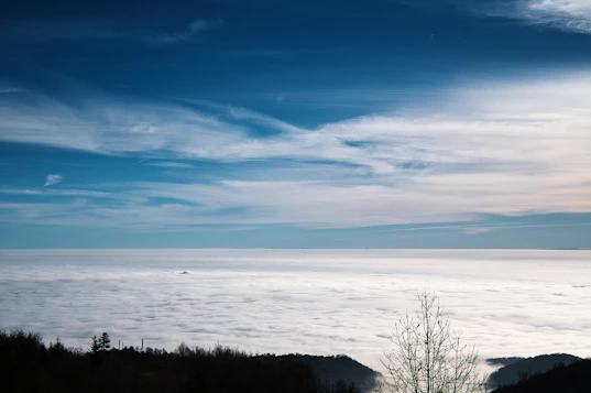 Sea of clouds with distant mountains and blue sky