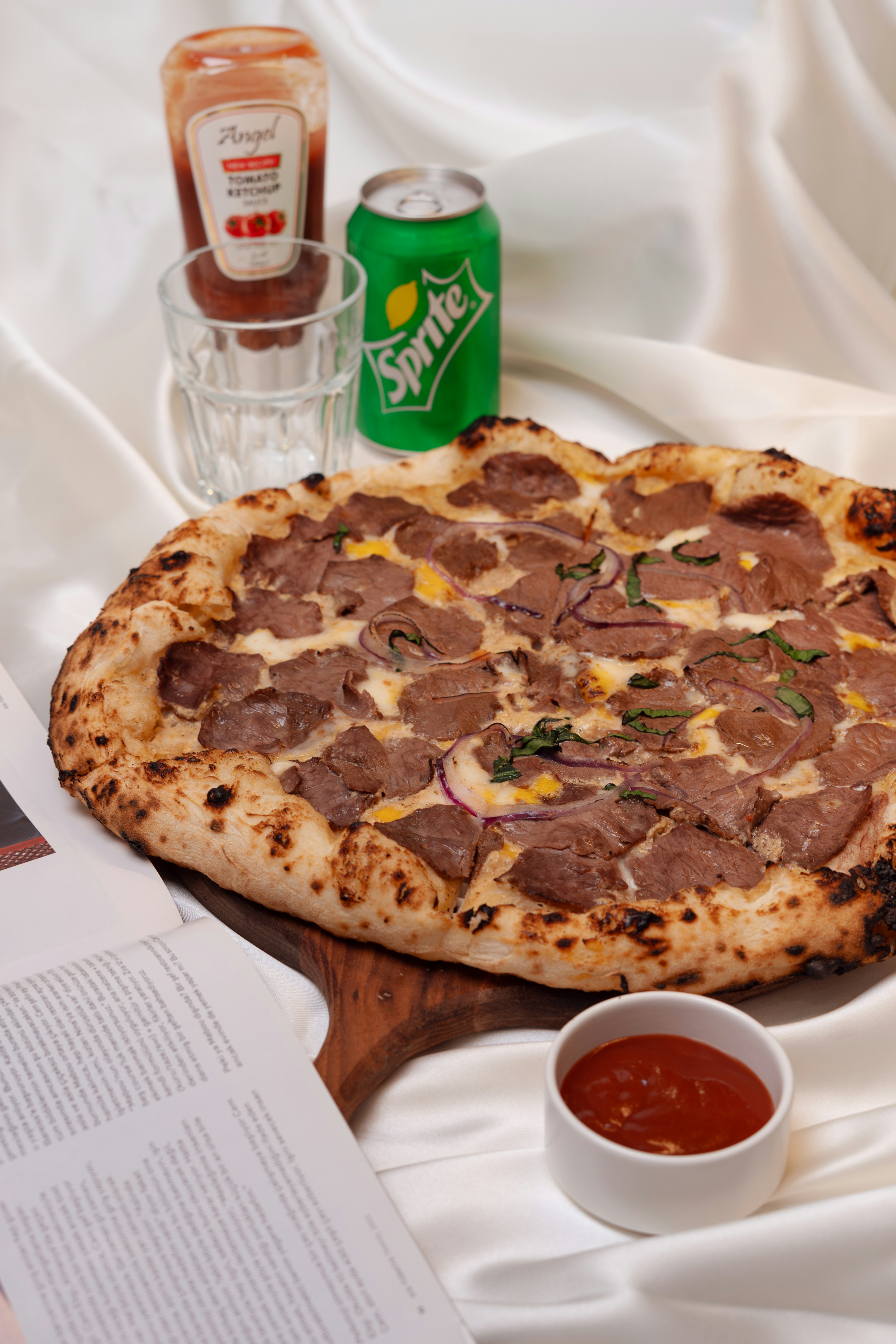 A delicious pizza with a can of sprite and ketchup.