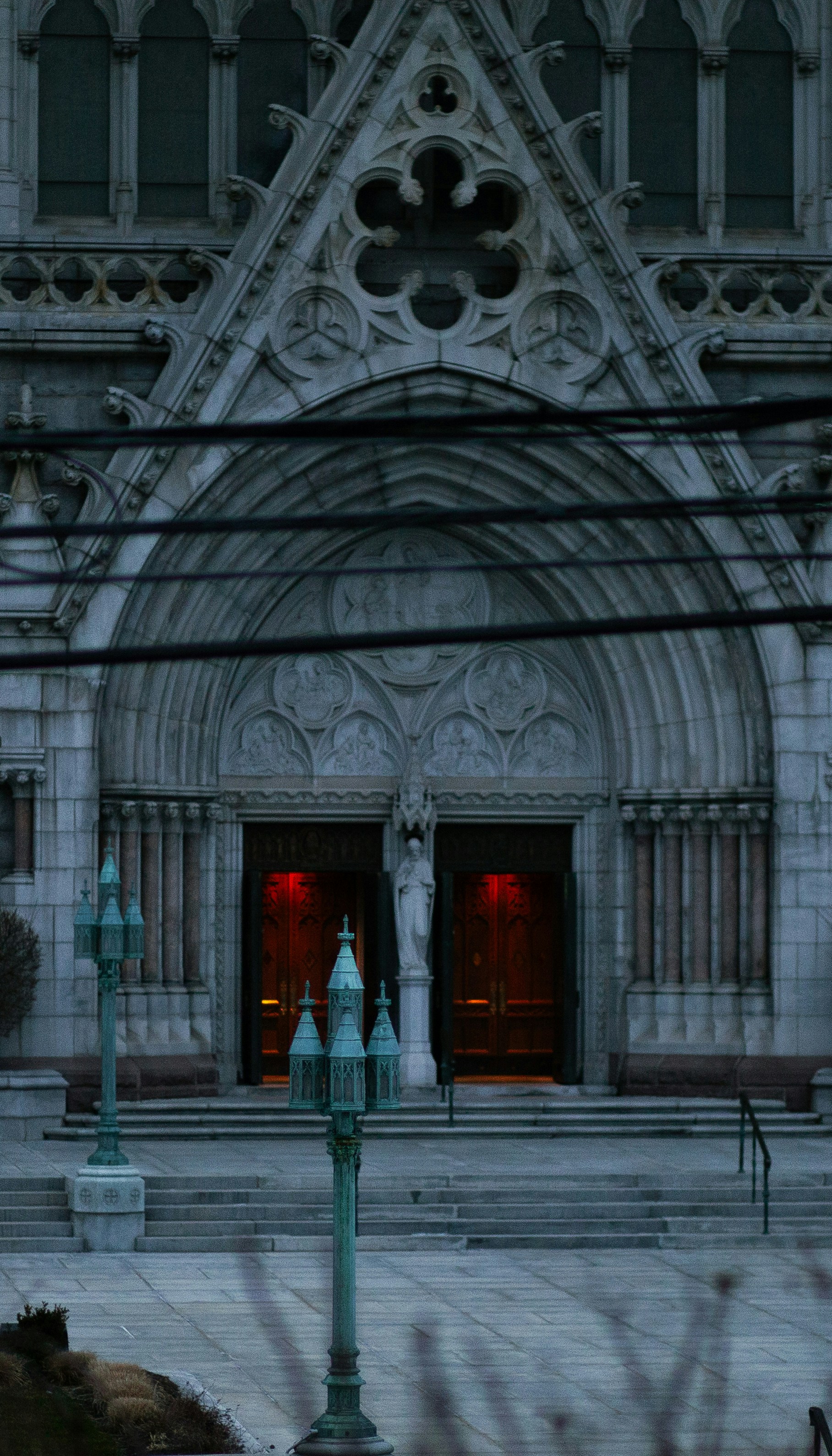 Gothic cathedral entrance with ornate stonework and red-lit doors