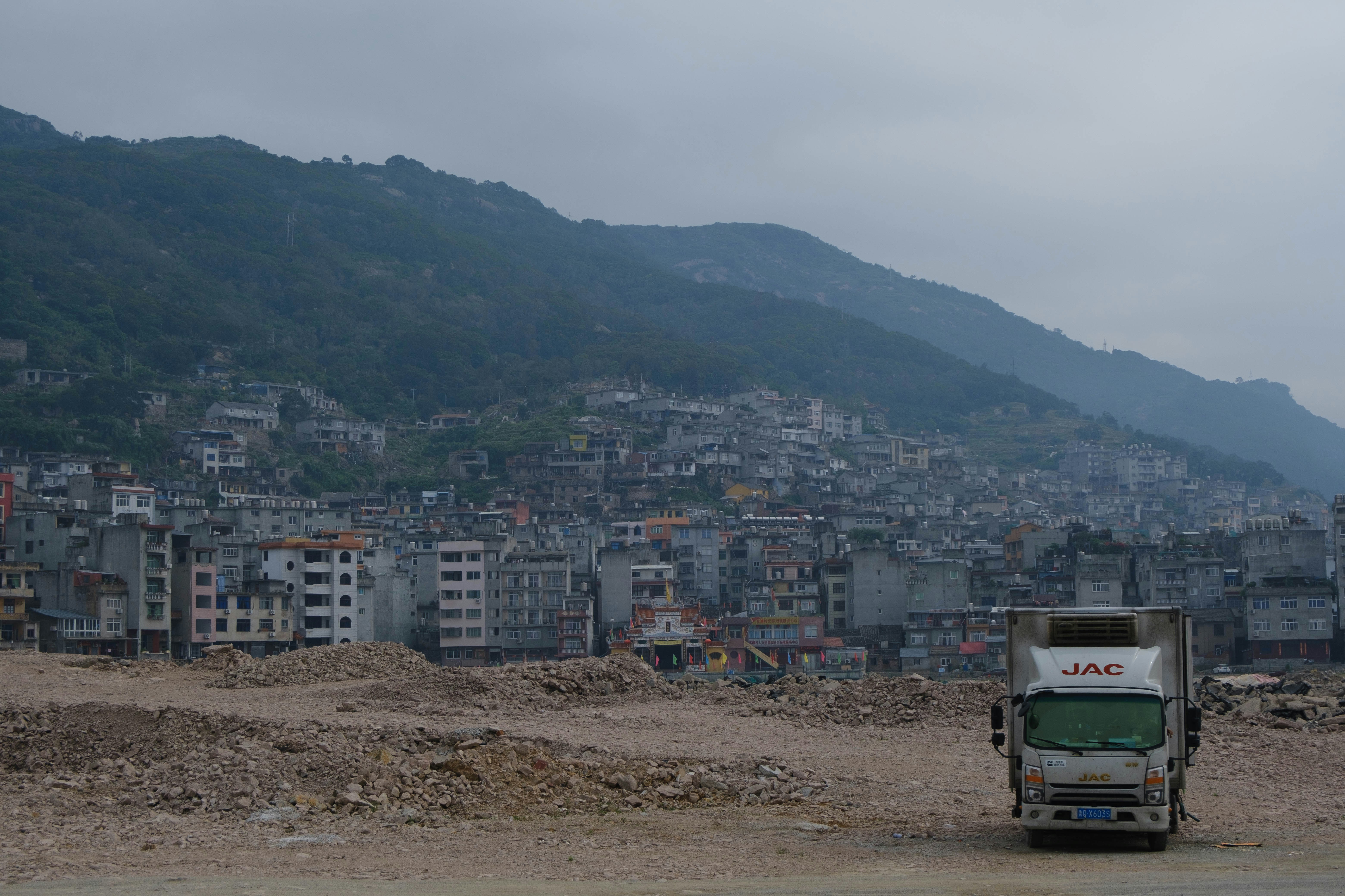 Truck on dusty ground with city on hillside