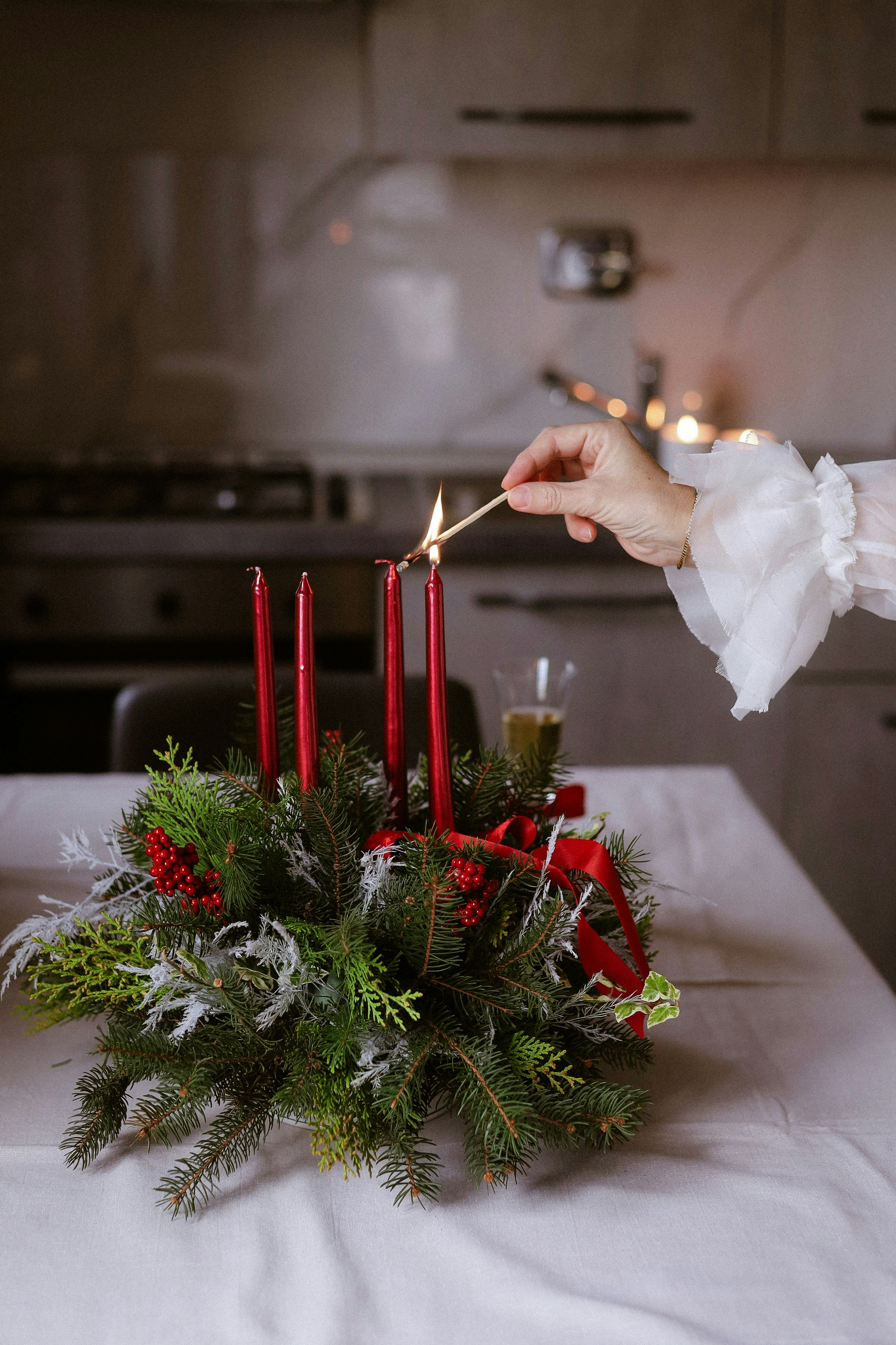Hand lighting red candles on advent wreath