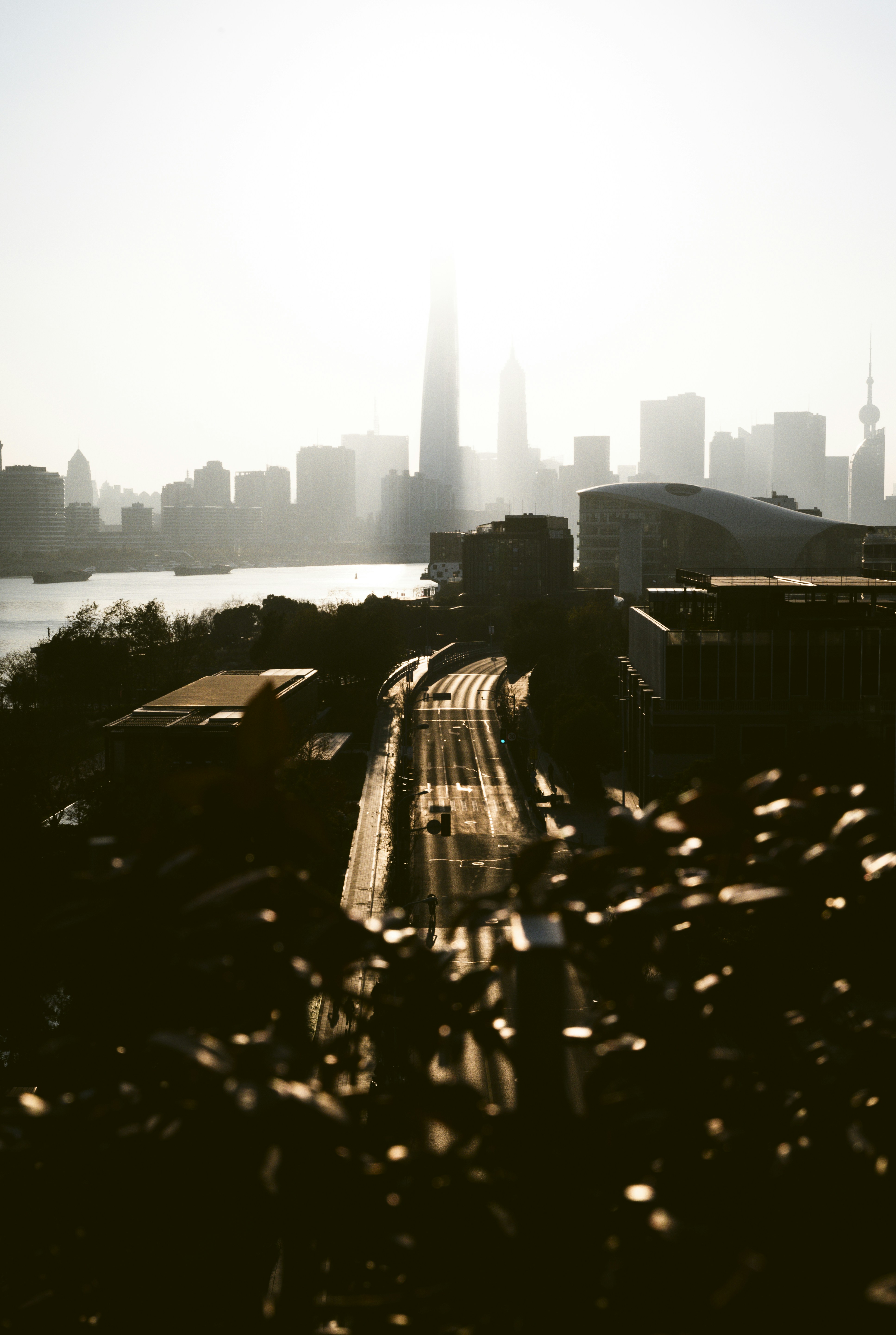 Sunlight streams over a city skyline and river.