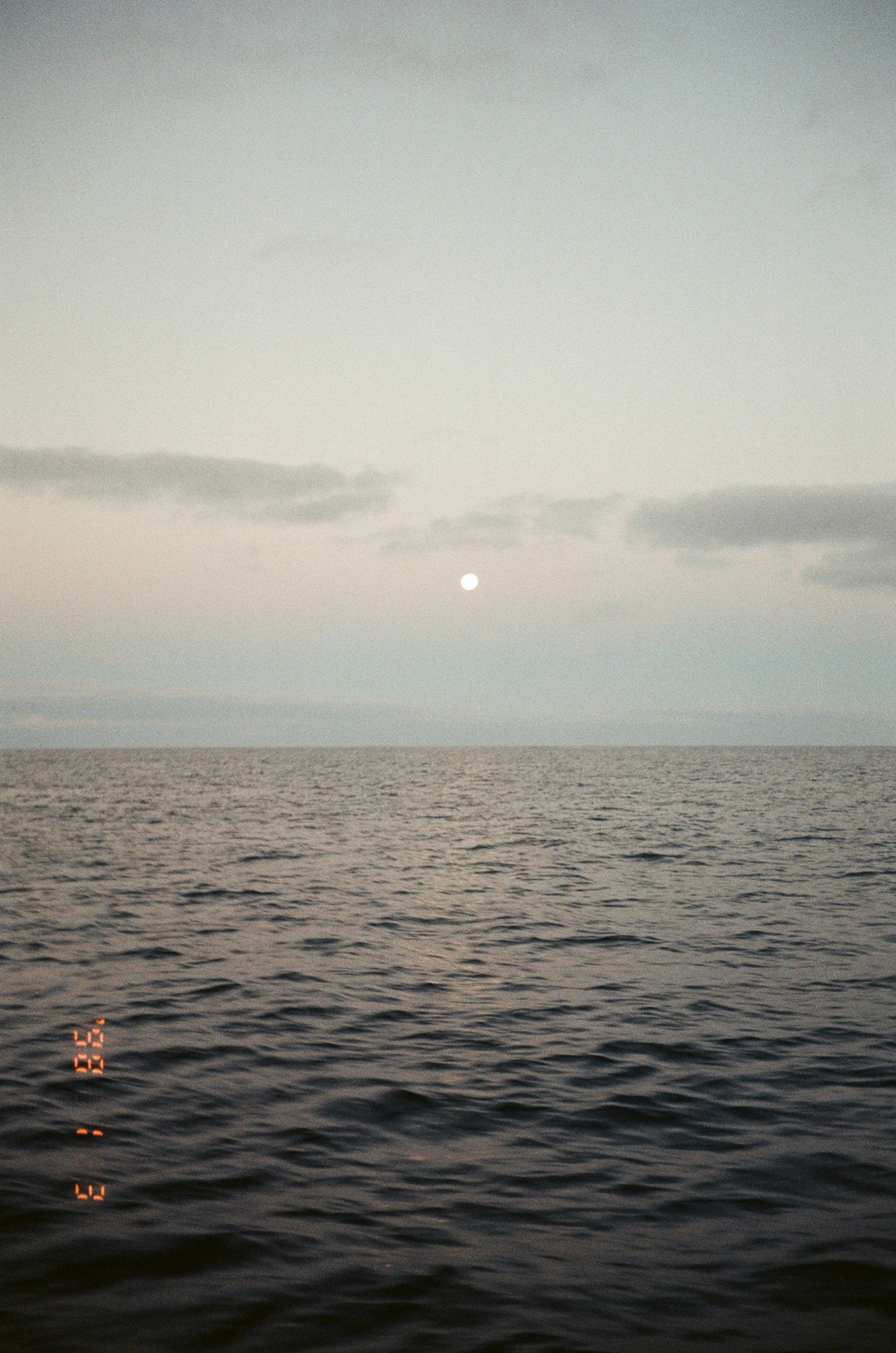 Full moon over the calm ocean at dusk