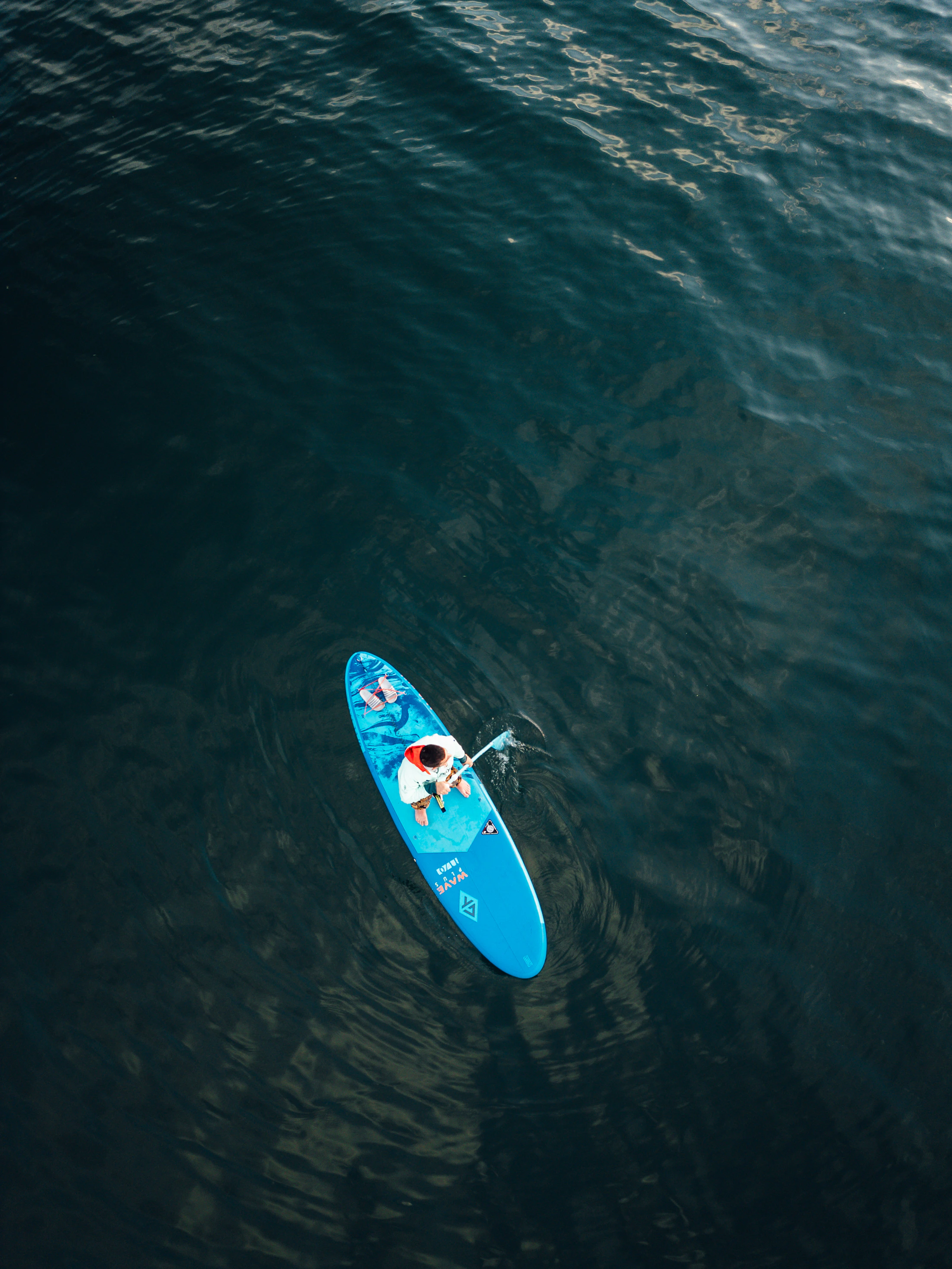 Paddleboarder moving across deep blue open water