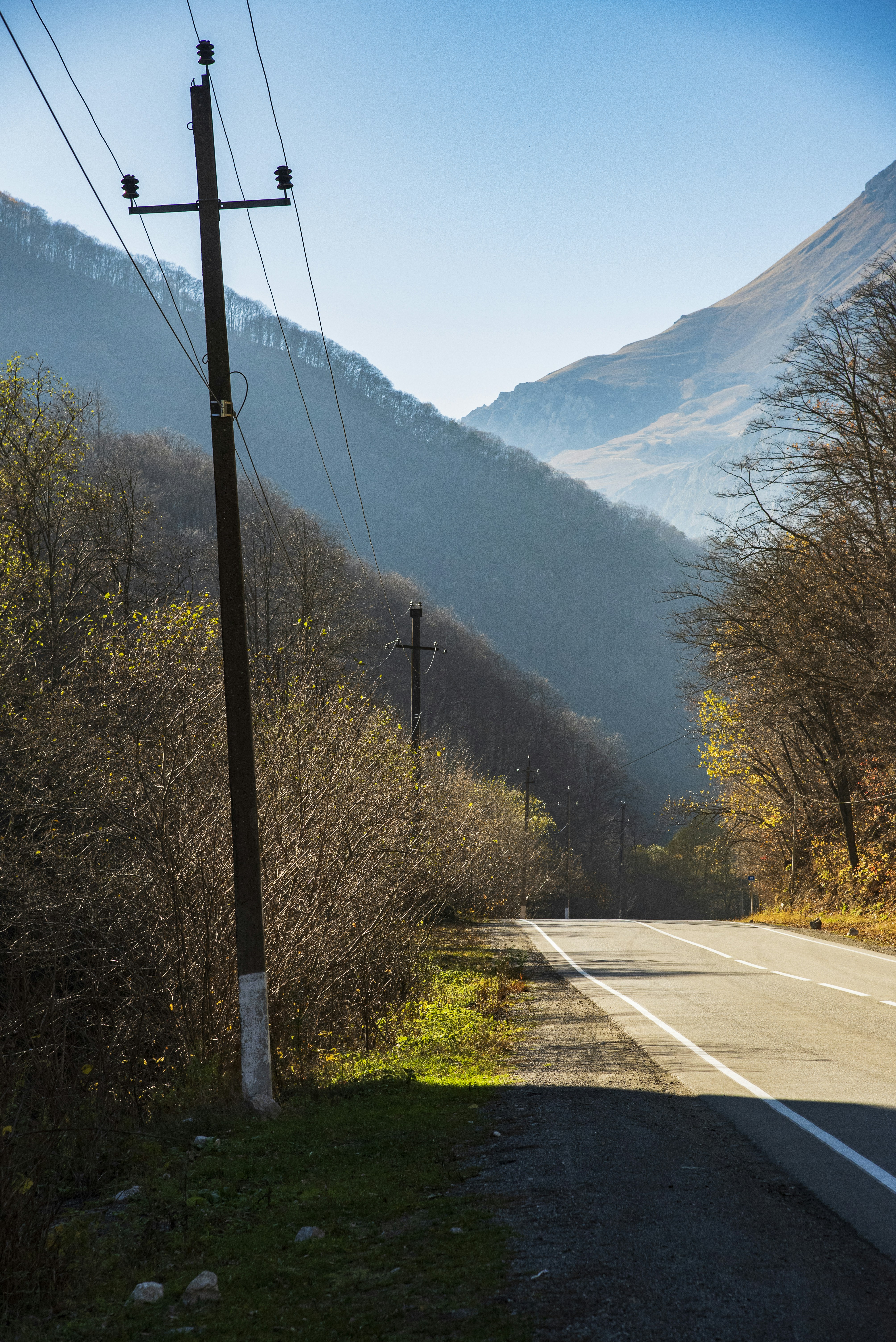 Road through a mountain valley with power lines.