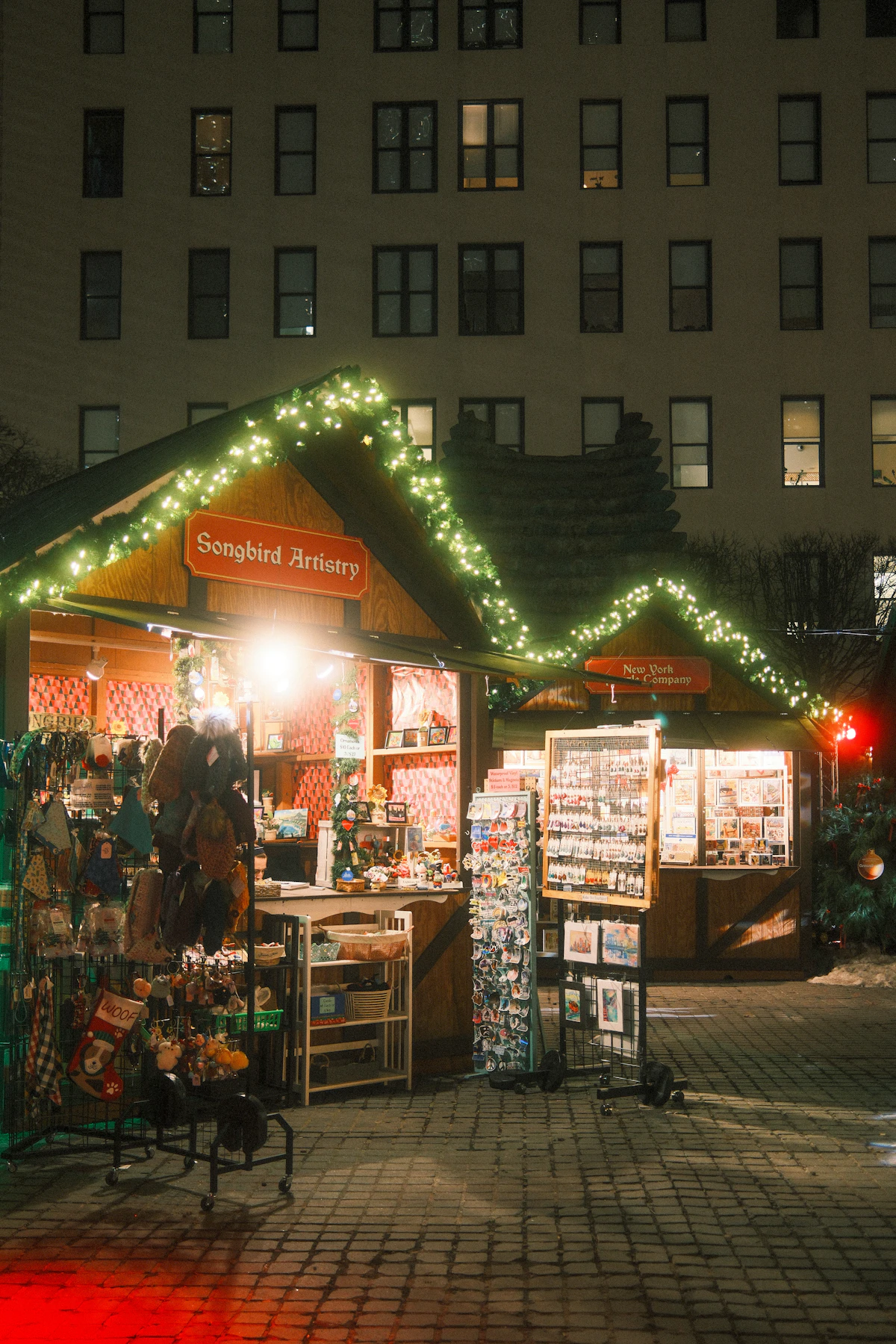 A wooden holiday market stall trimmed with string lights at night