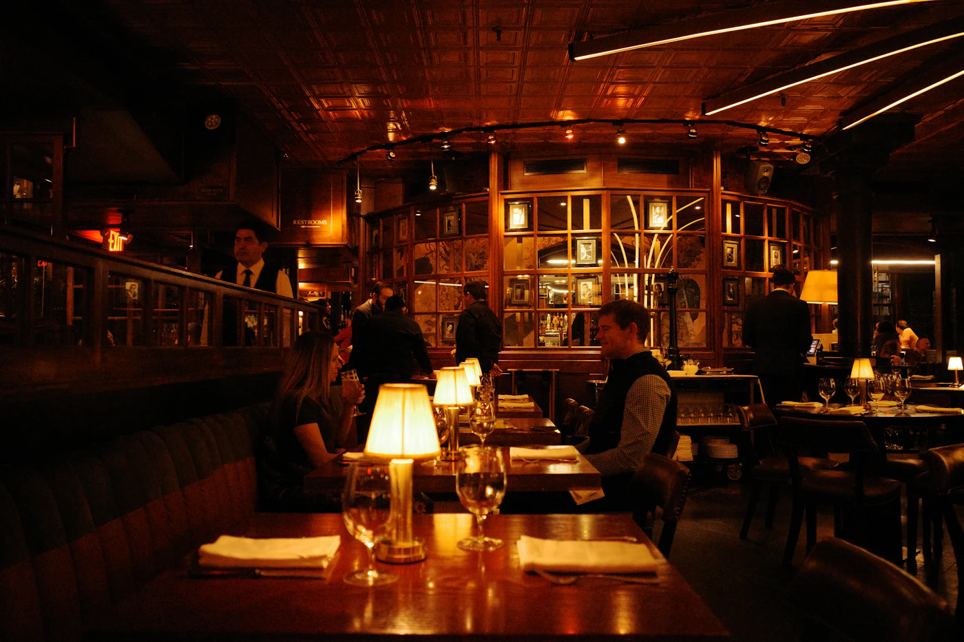 A warmly lit restaurant dining room with guests at tables