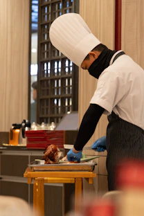 Chef carves roasted duck in a kitchen.