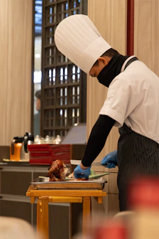 Chef carves roasted duck in a kitchen.