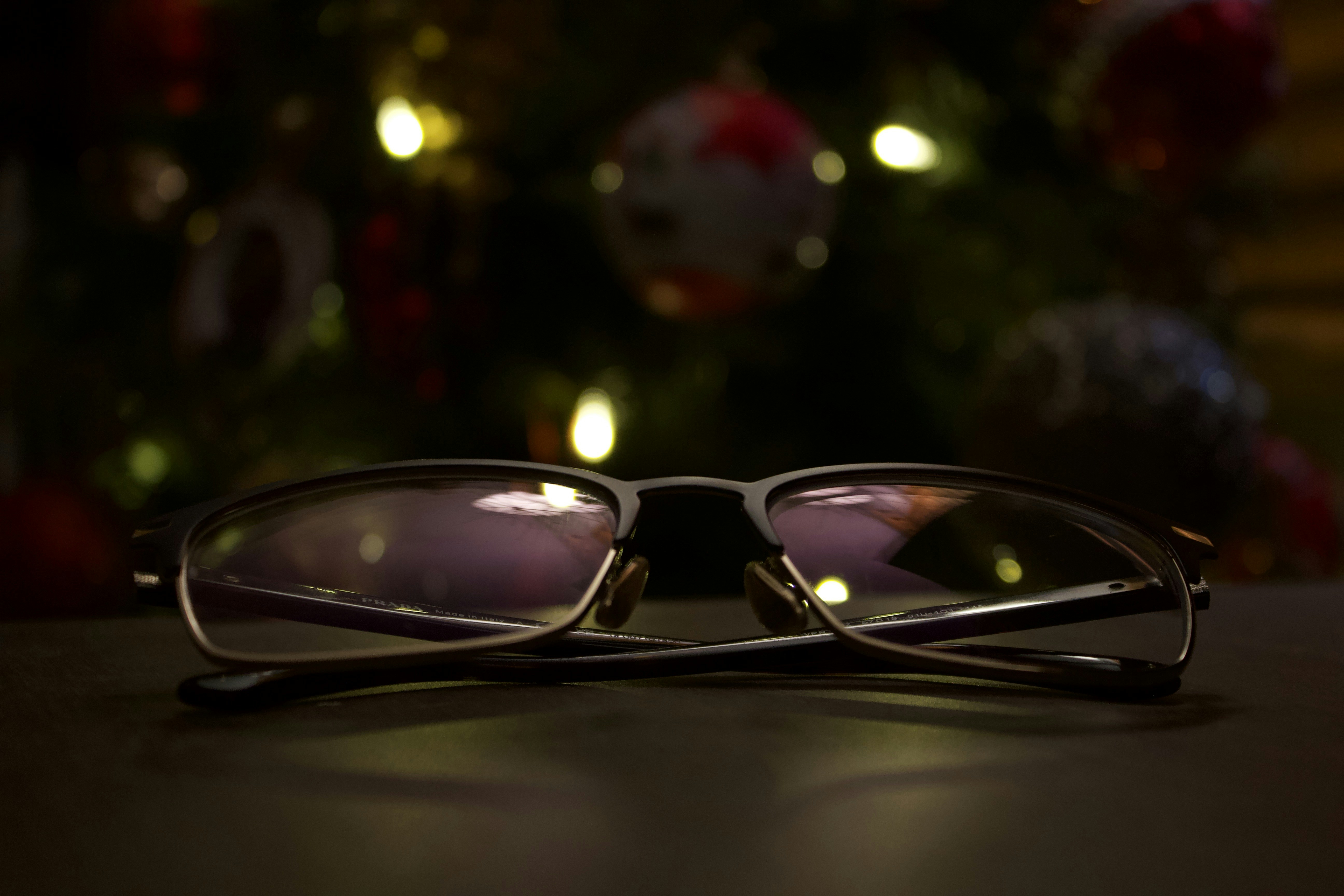 クリスマスライトが灯されたテーブルの上に置かれた眼鏡