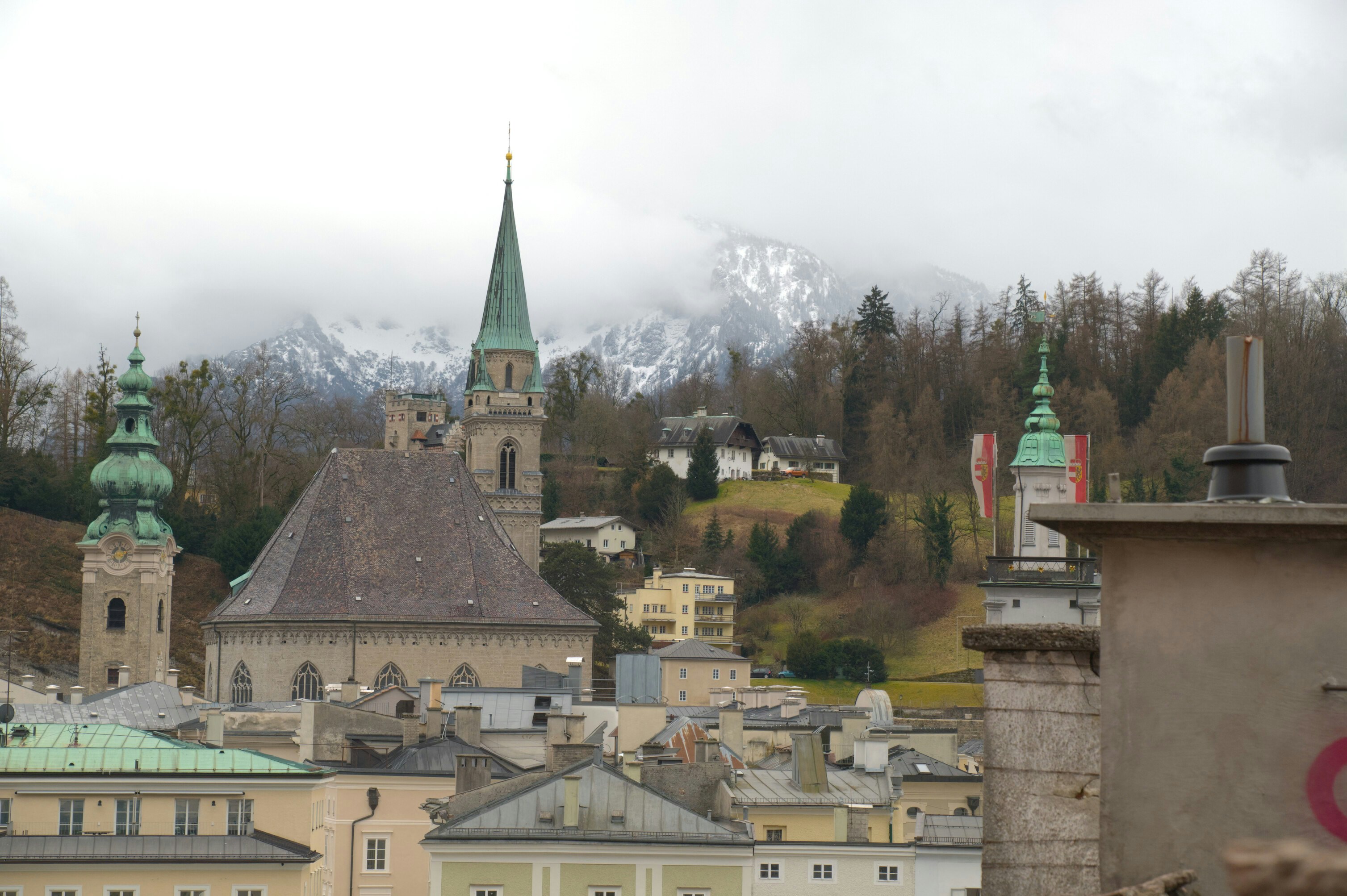 Historic european city skyline with church spires and mountains.