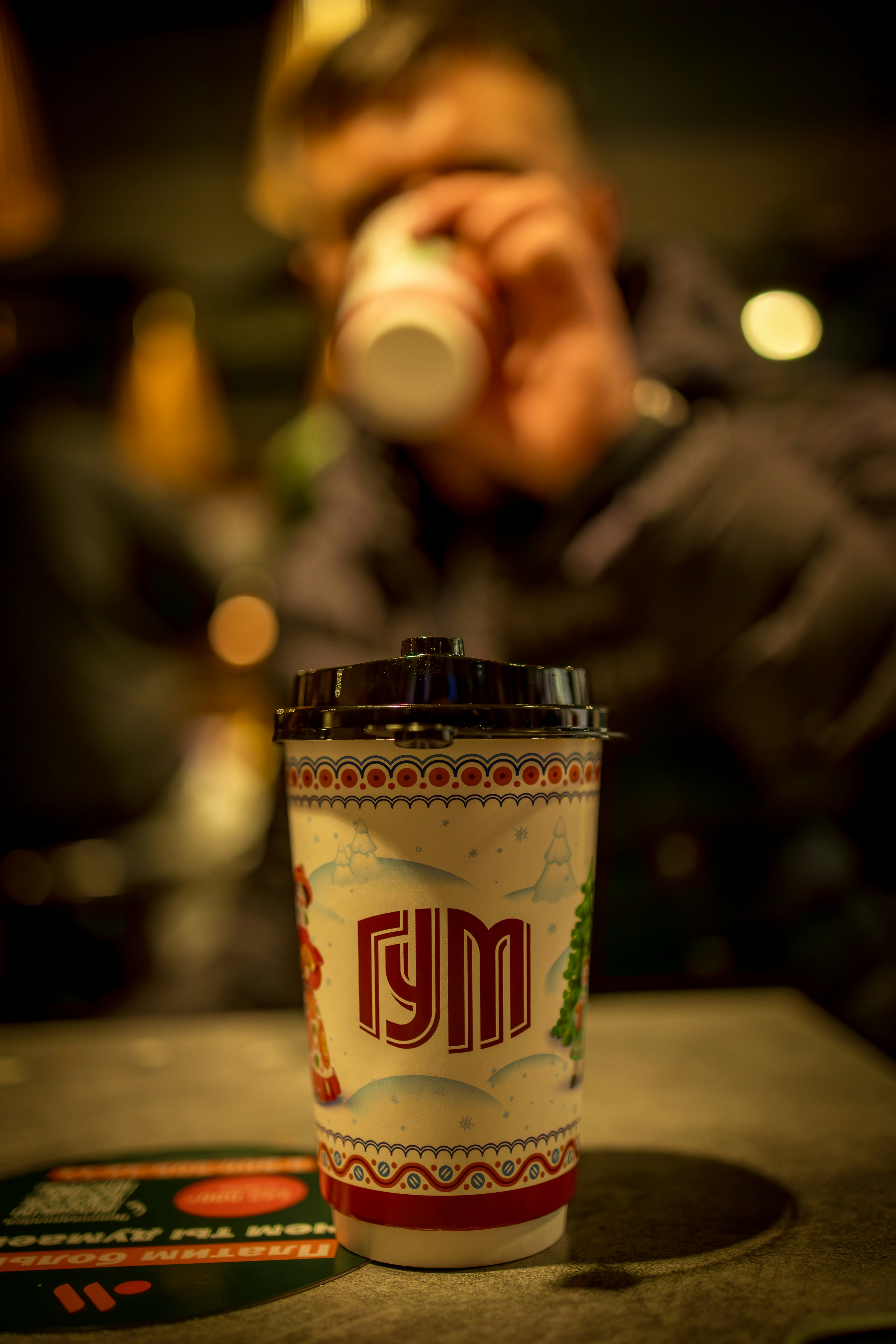 Person drinking from a decorated paper cup