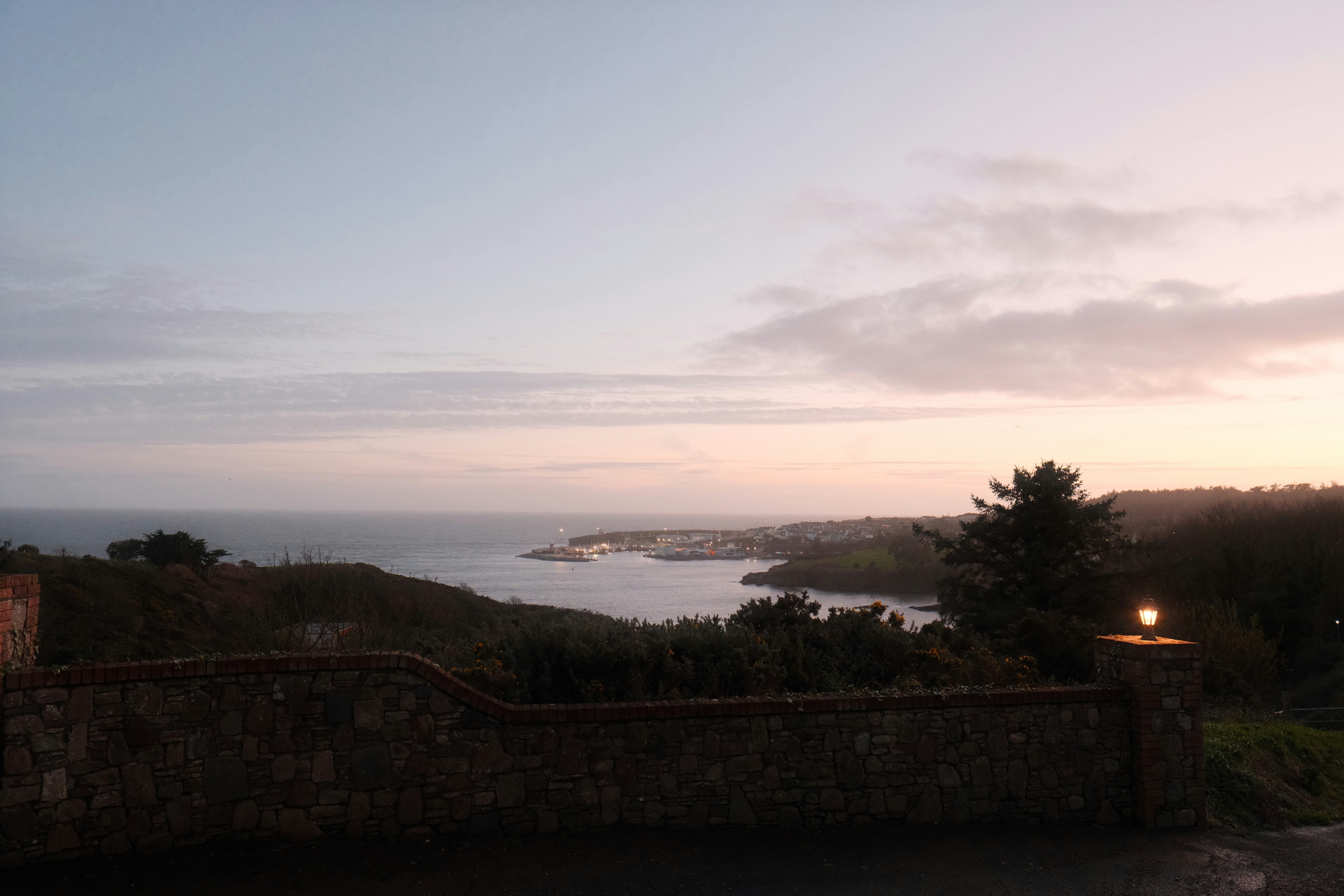 Bahía tranquila con barcos lejanos al anochecer