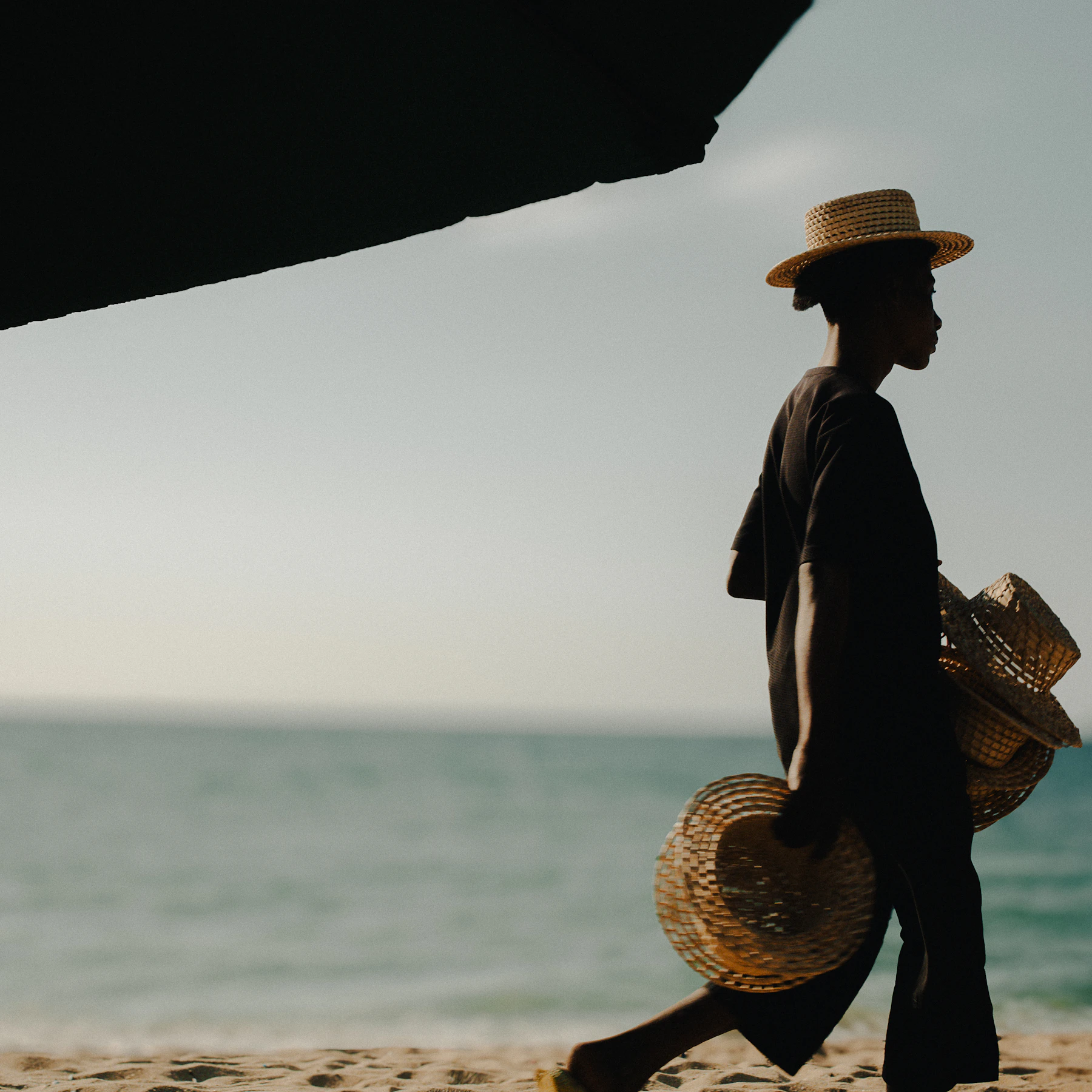 Woman in a straw sun hat walking along the shoreline
