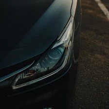Close-up of a dark car headlight at sunset
